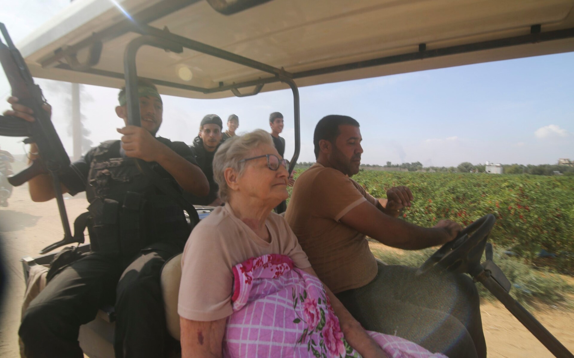 An elderly Israeli woman appears unnaturally calm as she is driven by armed men into the Gaza Strip on a golf cart. Photo / AP