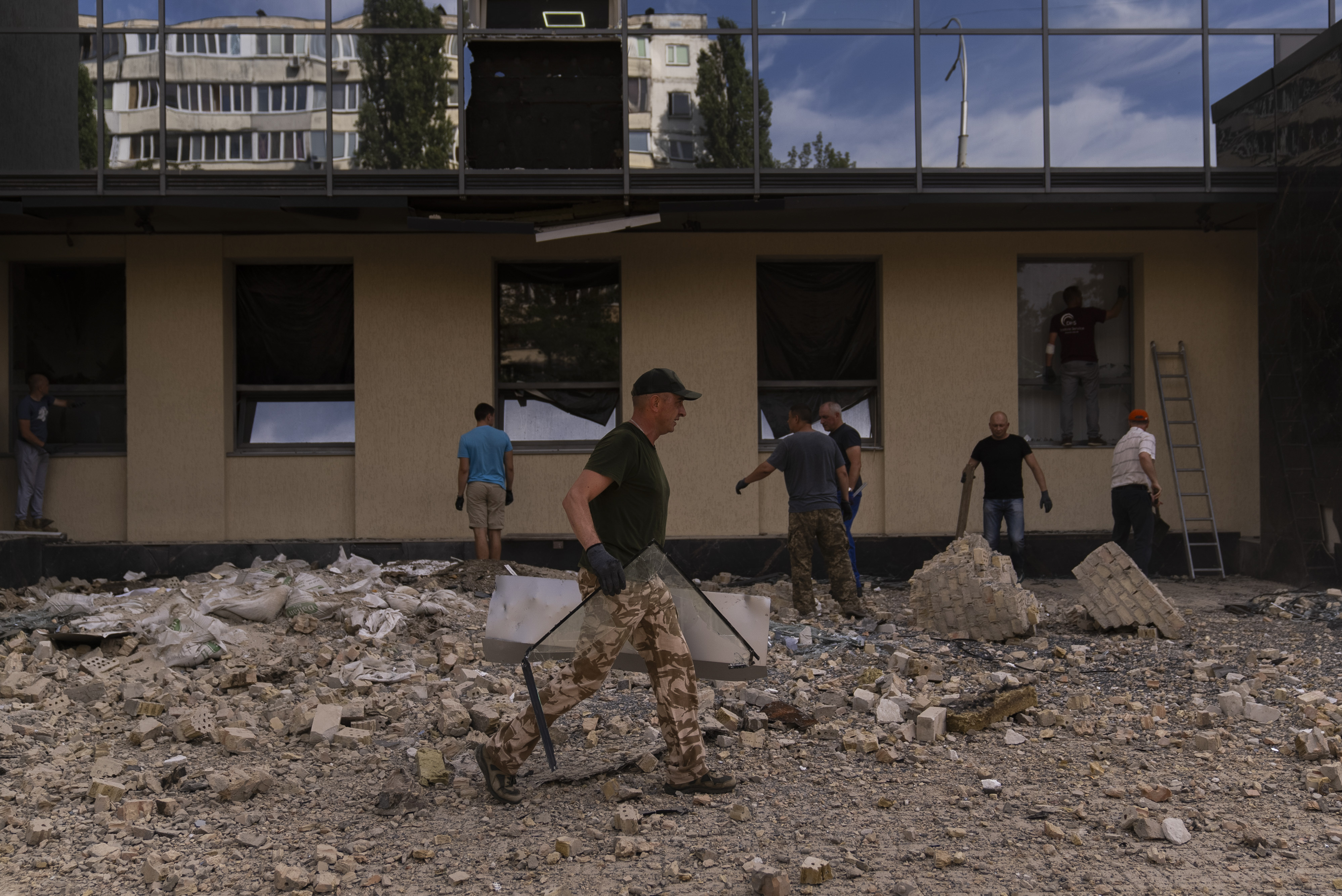 People clean up debris outside a damaged government building in Kyiv, Ukraine on Wednesday, August 2, 2023, following Russian drone attacks. Photo / AP