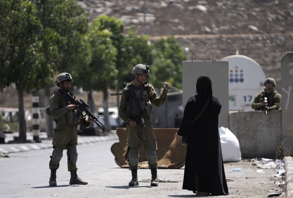 Israeli soldiers speak to a Palestinian woman near the site of an alleged car-ramming attack near Beit Hagai, a Jewish settlement in the hills south of the large Palestinian city of Hebron, Wednesday, Aug. 30, 2023. (AP Photo/Mahmoud Illean, File)