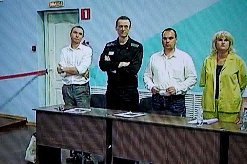 Russian opposition leader Alexei Navalny seen on a TV screen standing among his lawyers, as he appears via video link. He was convicted on extremism charges and sentenced to 19 years in prisons, in the harshest ruling against the imprisoned Kremlin critic to date. Photo / AP
