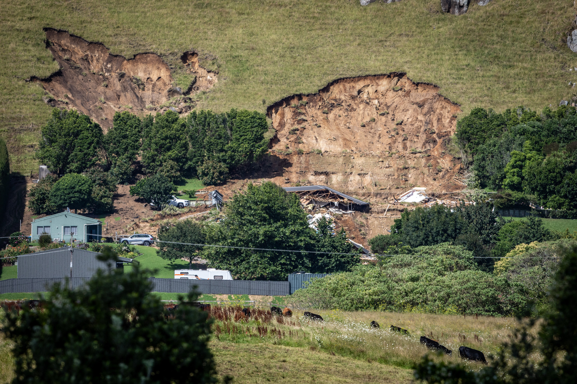 Images of the hillside above Welcome Bay Rd this morning show a home completely taken out by a large slip, but with a mangled roof and house frame still standing above the rubble. Photo / Michael Craig