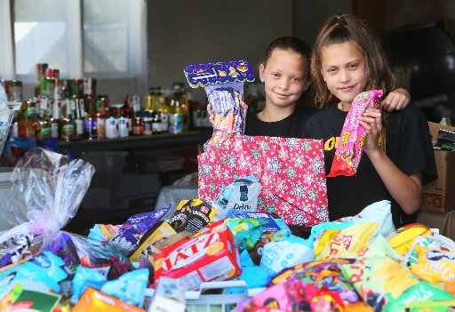 Sisters Ariya Beuker, 9, and Taya Beuker, 10, are helping Emily Johnson pack this year's Christmas kai boxes. Photo / Tania Whyte