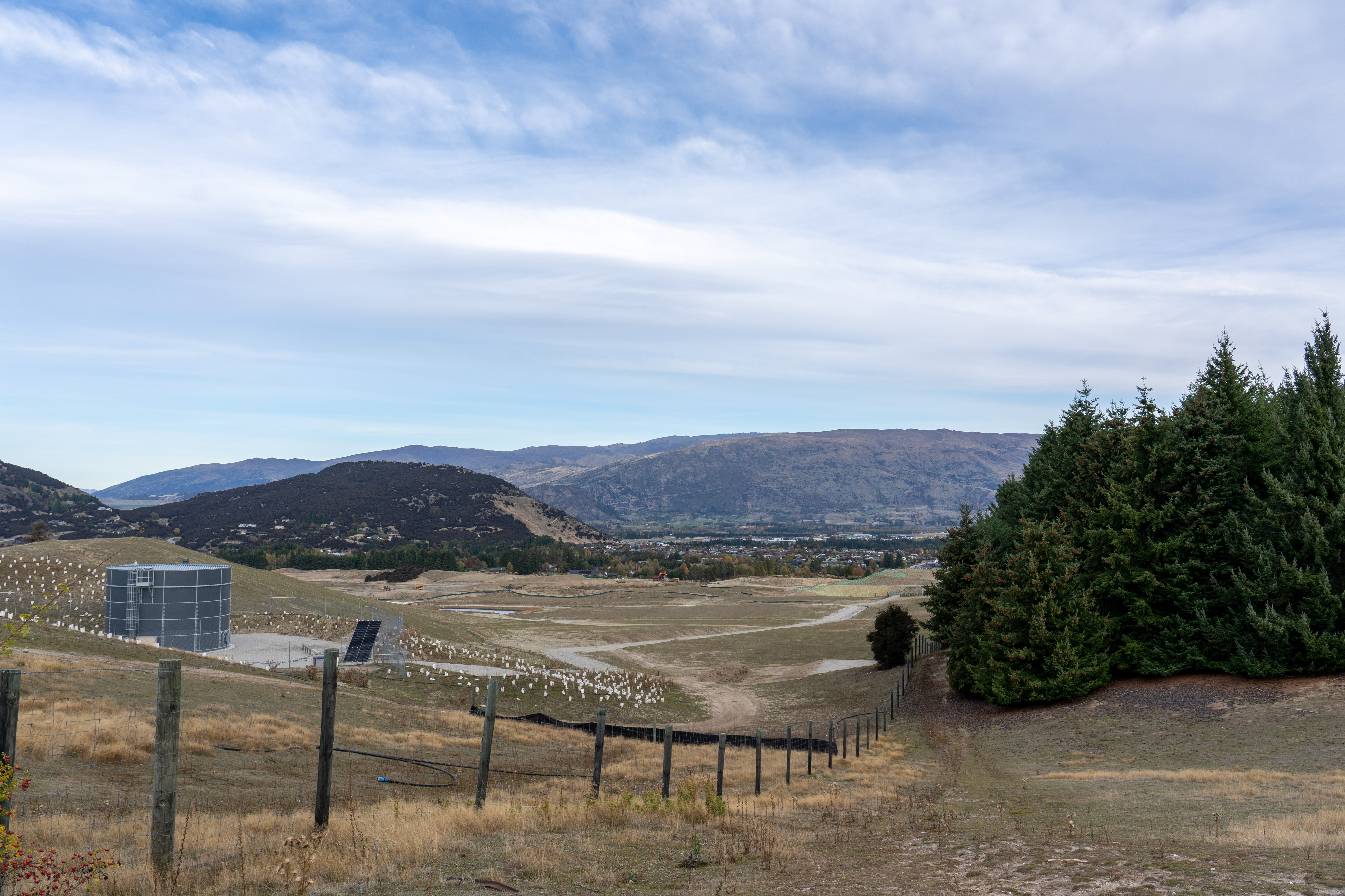 Winton Property Limited is developing the land in front of and left of the water tank into a retirement village, with Mt Iron and the Criffel Range providing a picturesque backdrop. A road will also be built to enable development into Sticky Forest, which includes the area in the foreground on the right of the fence. Photo / Derek Cheng