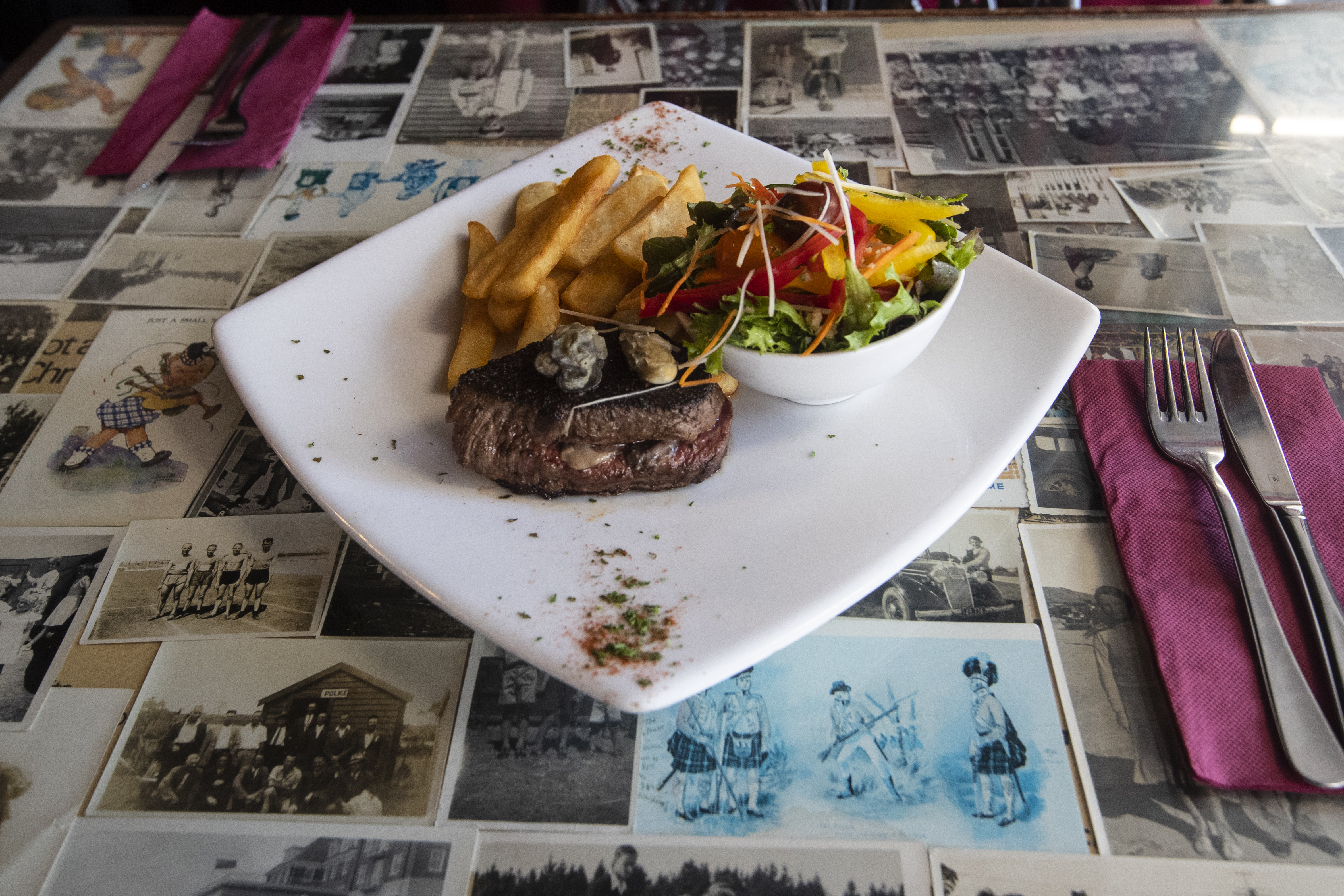 Tony's Carpet Bag steak sits on a table setting with owner Kenn Henderson's family photos. Photo / Jason Oxenham