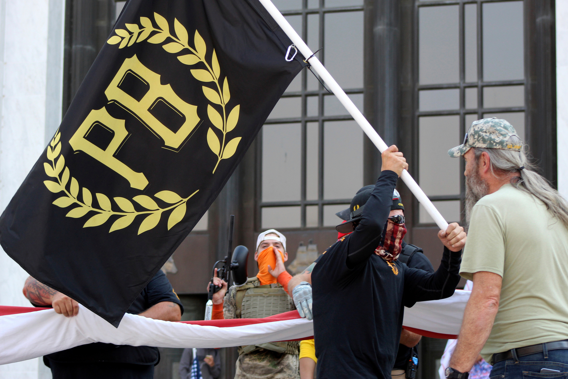 A protester carries a Proud Boys banner while other members start to unfurl a large US flag in front of the Oregon State Capitol in Salem. Photo / AP