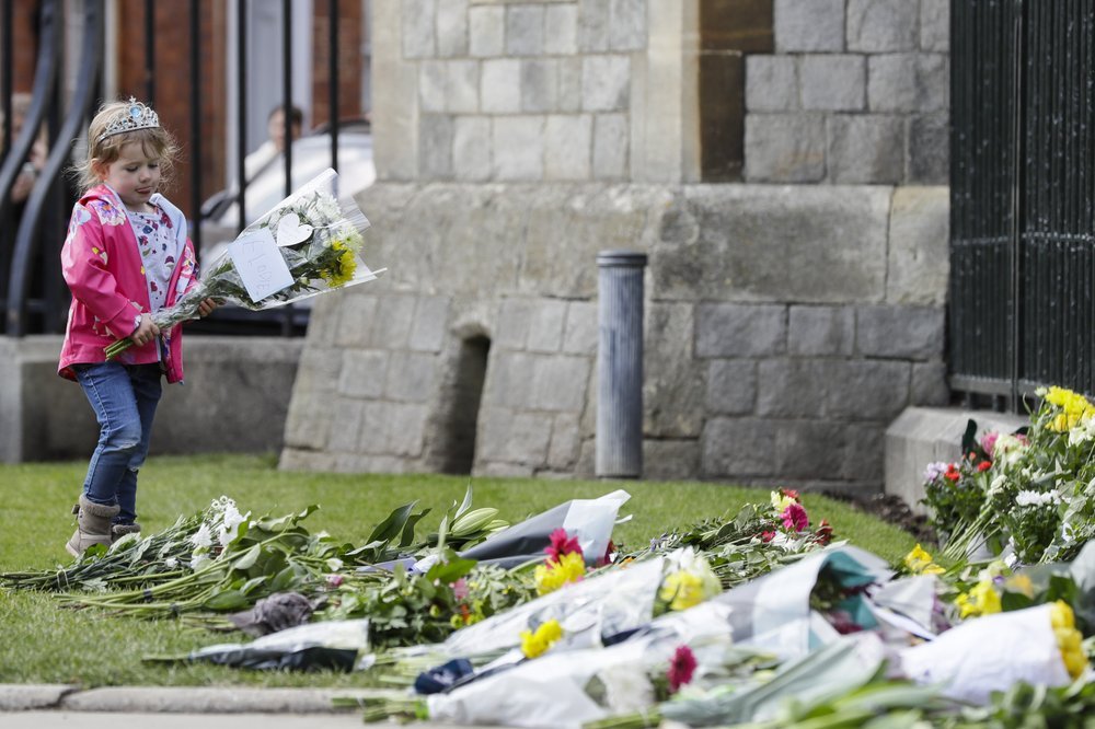 A young girl wearing a tiara lays flowers outside the Cambridge gate of Windsor Castle. Photo / AP