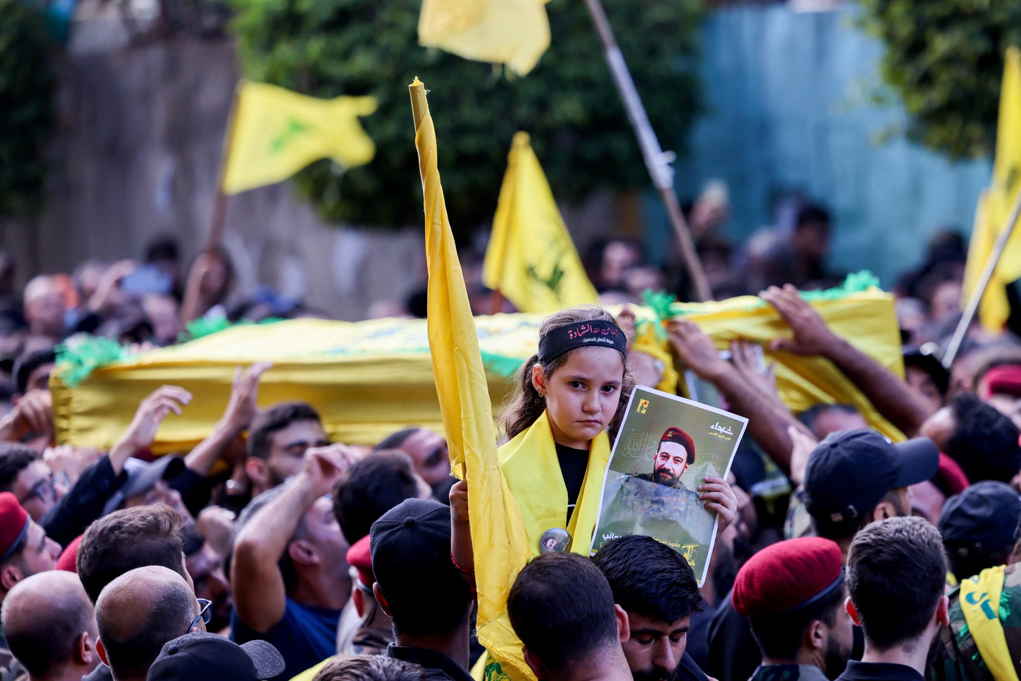 A girl carries a picture of a member of the Lebanese Shiite Movement Hezbollah who was killed in an Israeli strike a day earlier, as mourners carry his coffin during his funeral procession in the southern suburbs of Beirut on September 21. Photo / AFP