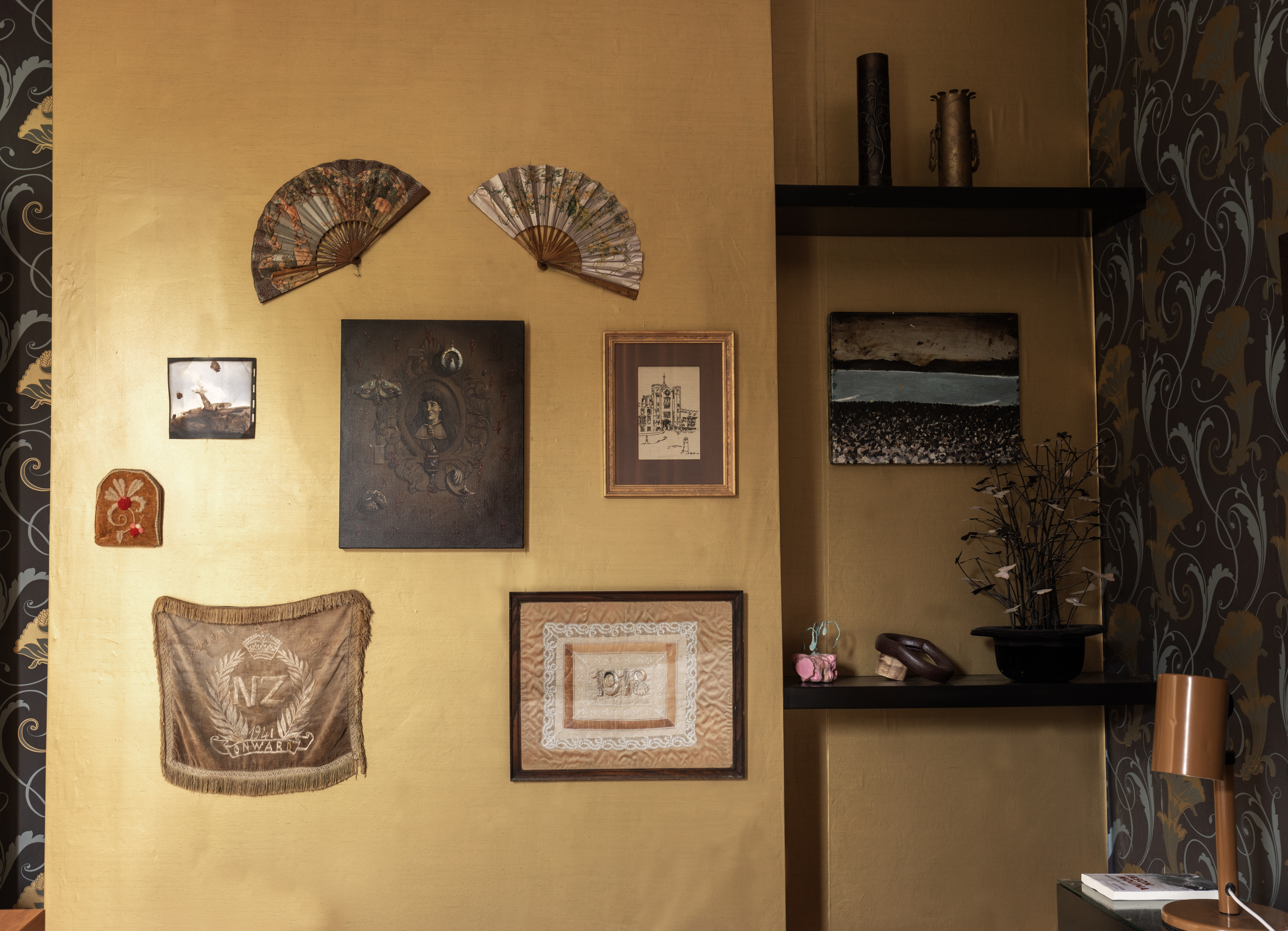 A bedroom is an ideal setting for textile artwork. Pictured: An embroidery and backstitch by Muriel Wallace, paintings by Garry Currin and Maryrose Crook and two antique fans and wartime embroideries, which take centre stage. In the right alcove, a painting by Richard Lewer and a sculpture by Dan Arps and Peter Madden. Photo / Ginny Fisher
