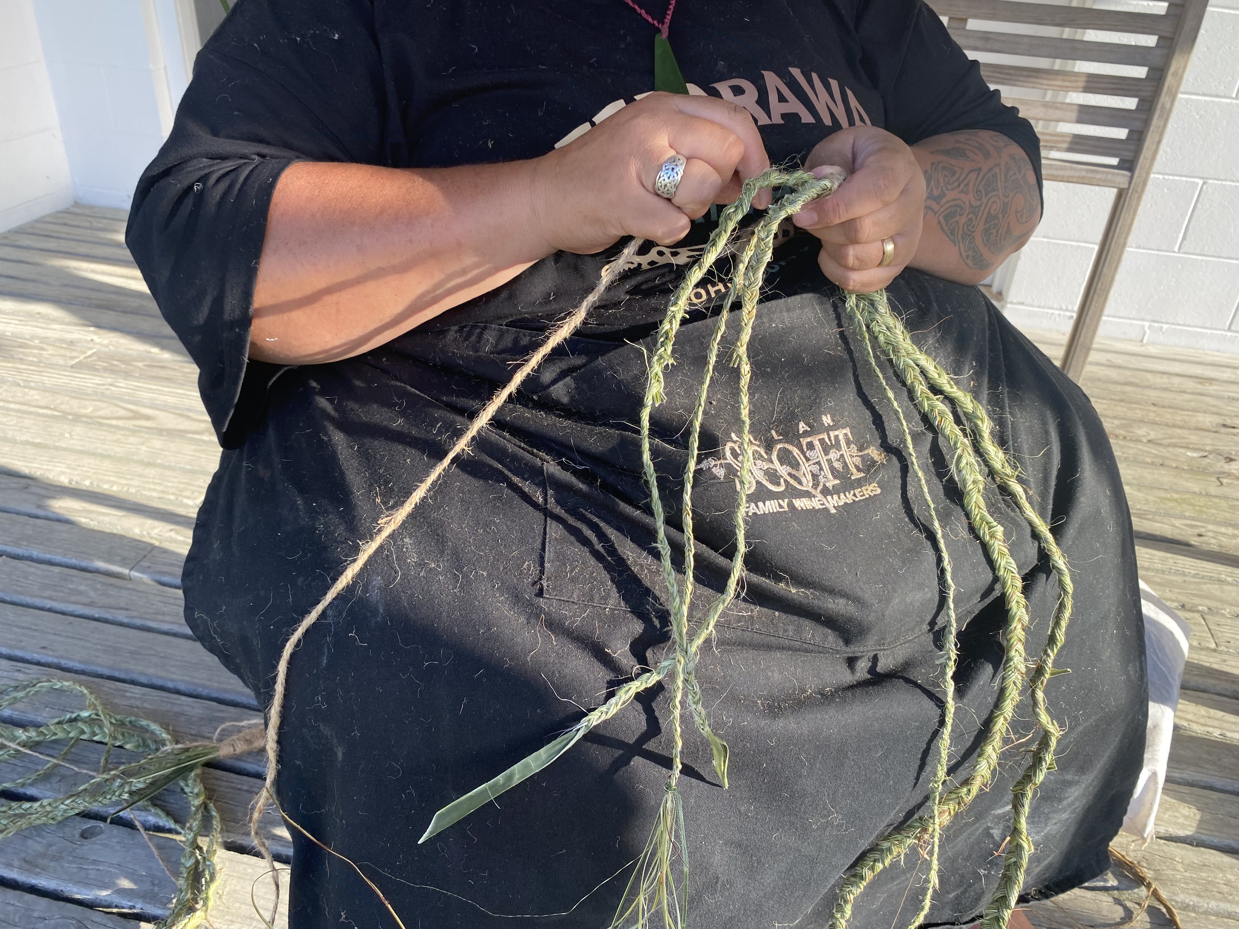 Flax is threaded into rope to hang on the back of the waka for the procession. Photo / Julia Gabel