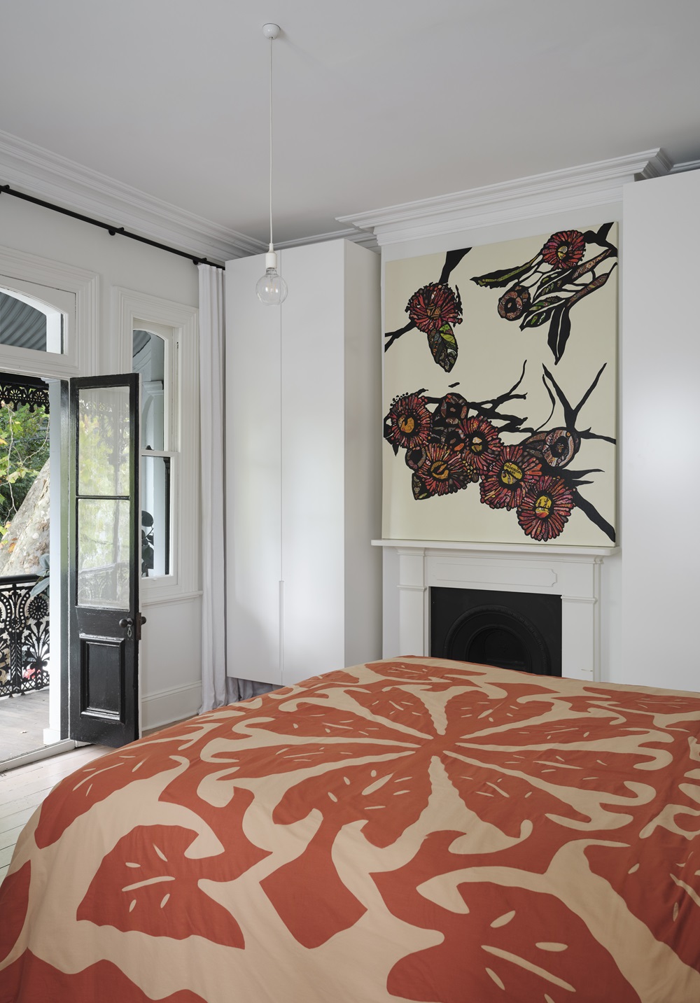 Inside the bedroom, a painting by Tony Albert hangs above the fireplace, while a tivaevae hand-stitched bedspread by Vehia Tuhei-Faahu adds colour to the room.