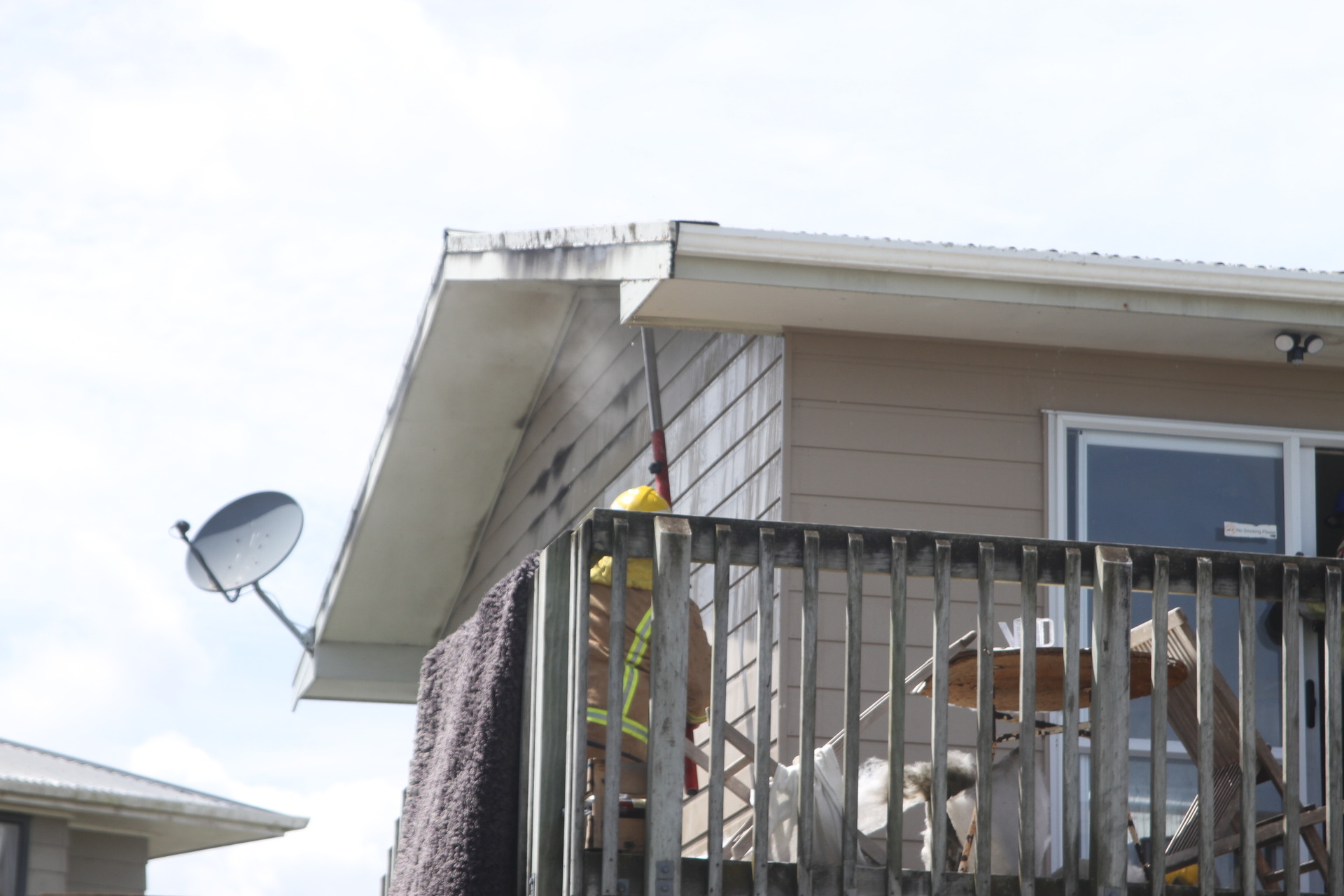 A firefighter breaking into the roof cavity from outside the house to get at yesterday's fire in Kaitaia. Photo / Peter Jackson