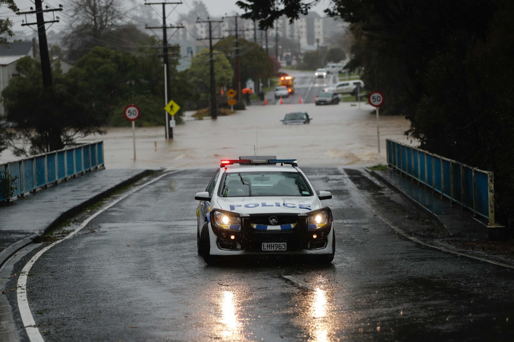 Car underwater and police checking on residents on Oraha Road, Kumeu. Photo / Dean Purcell
