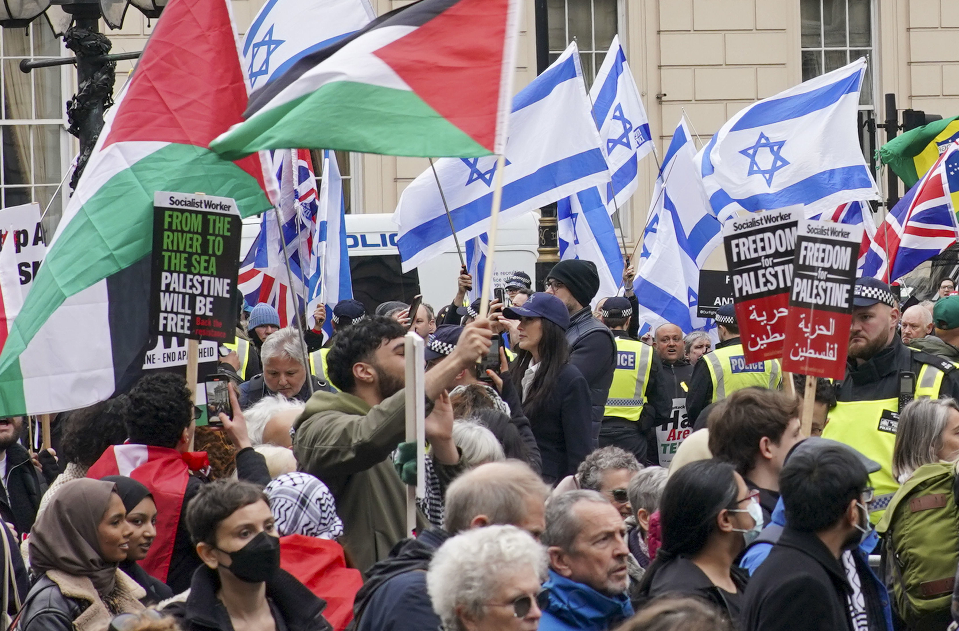 People take part in a pro-Palestine march as they walk past a counter-protest with Israeli flags, at Waterloo Place in central London. Photo / AP