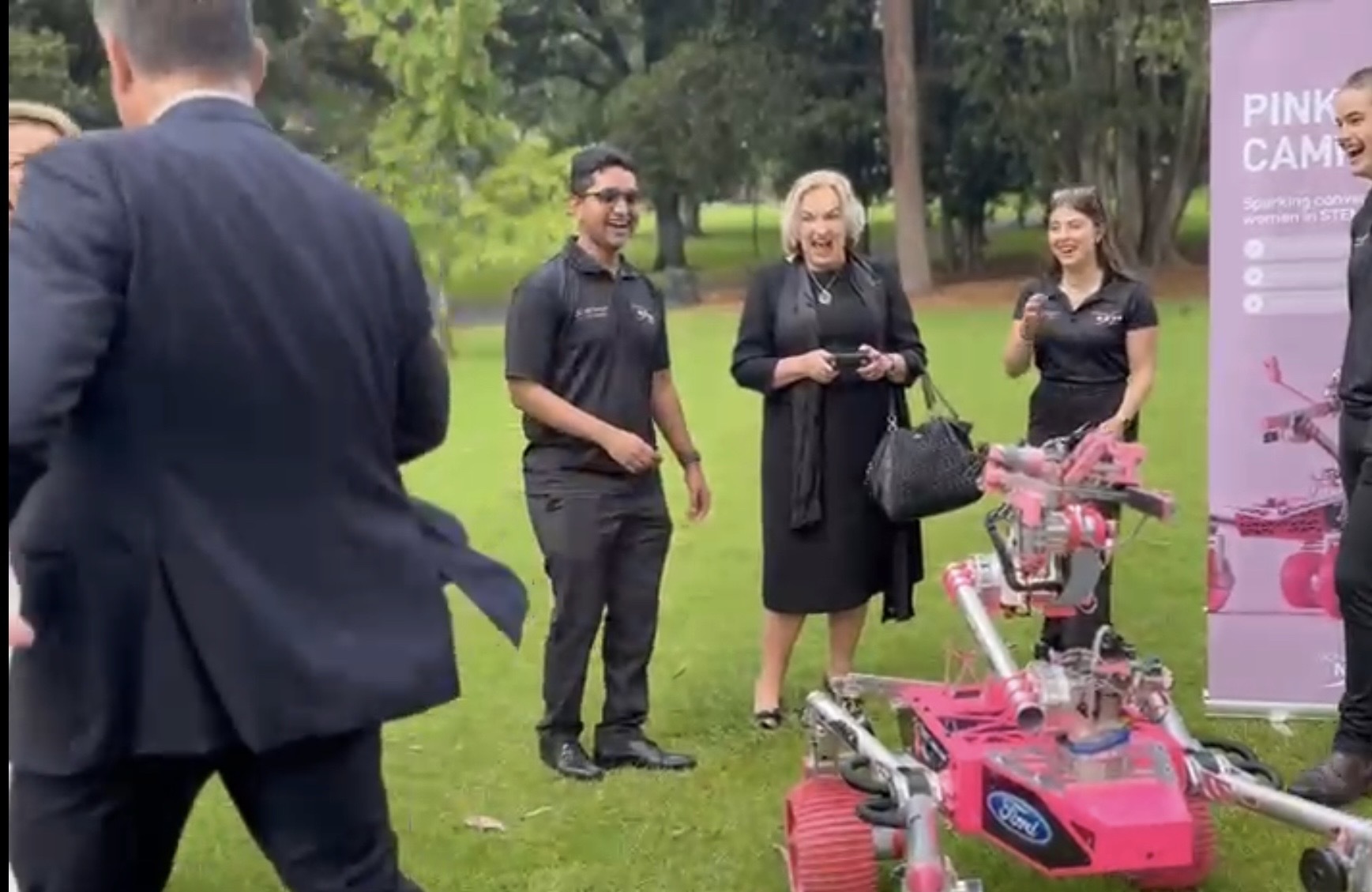 Australian Deputy Prime Minister Richard Marles evades Judith Collins piloting a pink Mars rover.
