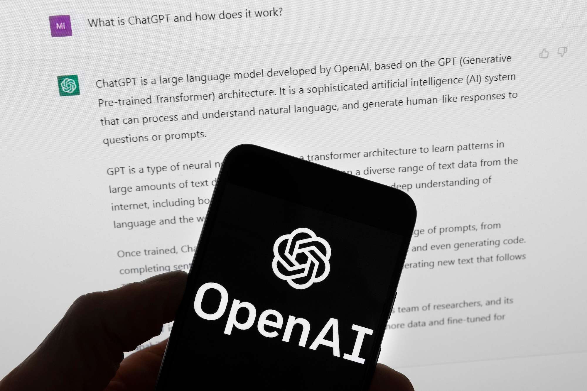 The OpenAI logo is seen on a mobile phone in front of a computer screen which displays output from ChatGPT. Photo / AP