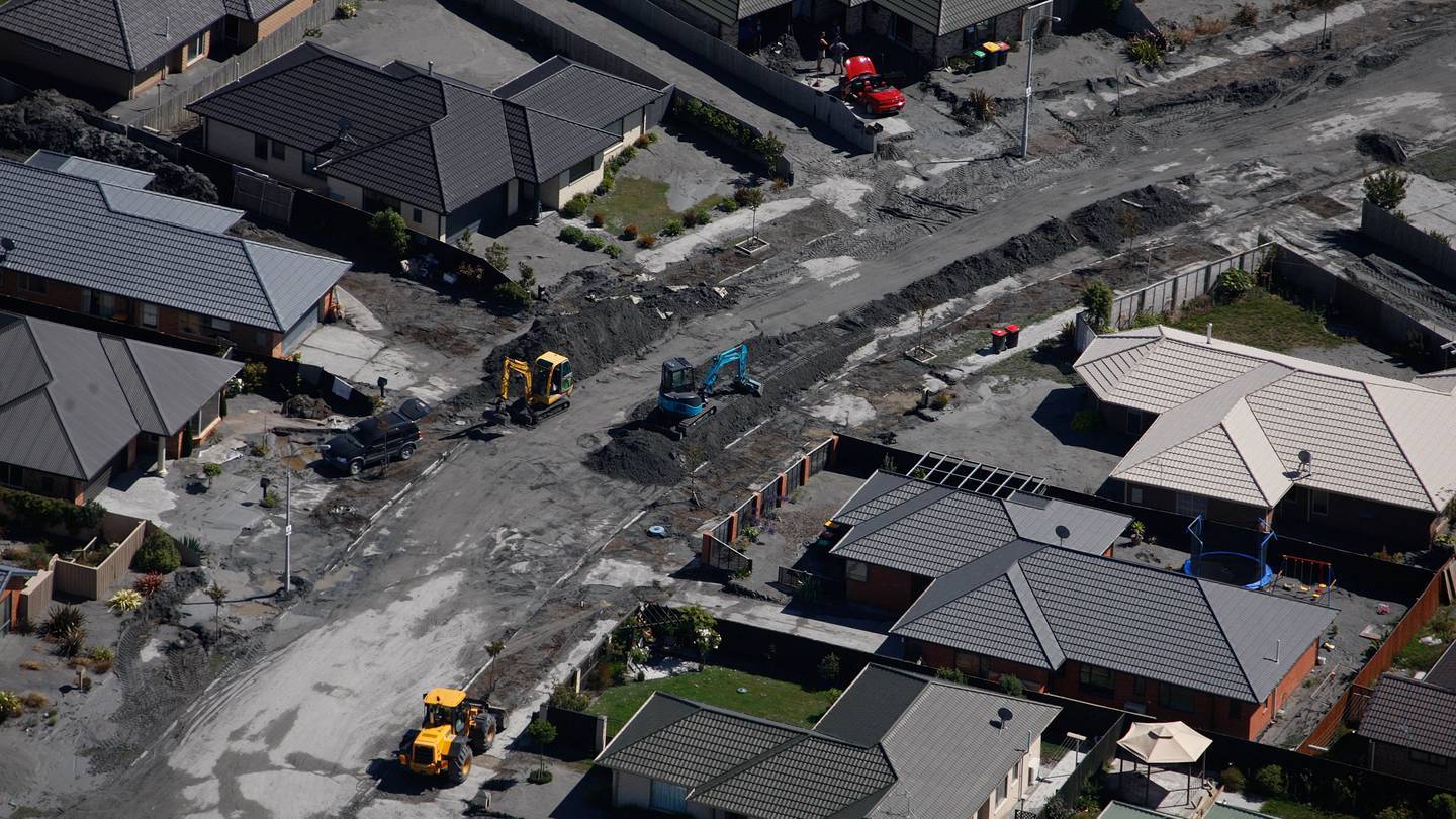 Workers clean up the black gunk which is caused by the liquefaction in Christchurch. Photo / Brett Phibbs