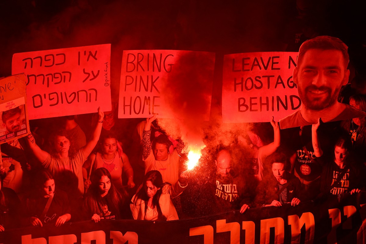 Demonstrators raise placards and light flares during a protest this week calling for action to release the remaining hostages held captive in Gaza. Photo / AFP