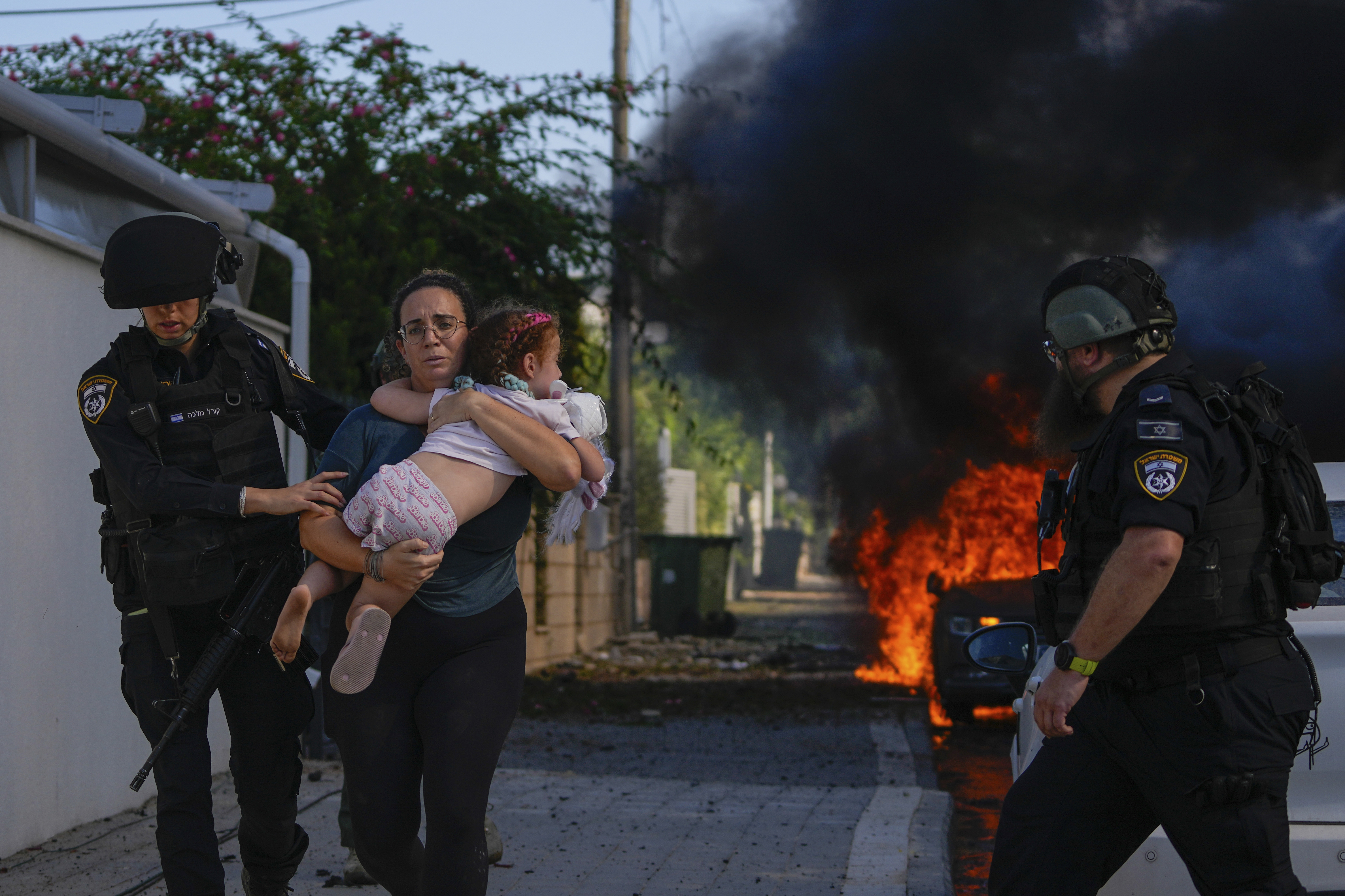 Police officers evacuate a woman and a child from a site hit by a rocket fired from the Gaza Strip. Photo / AP