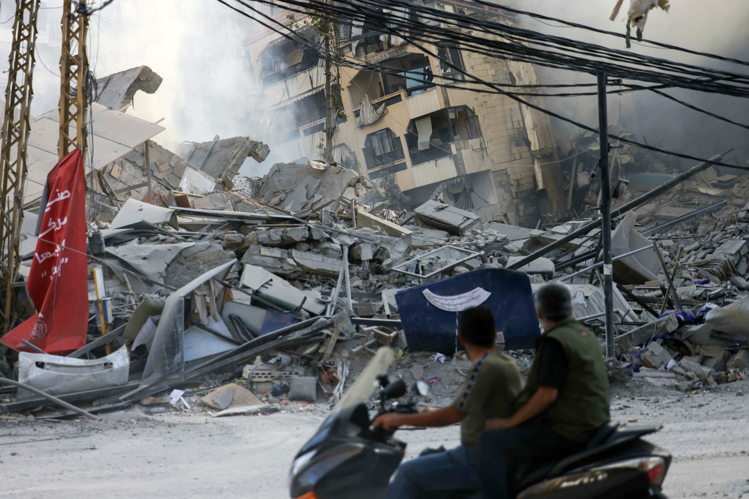 Men ride a motorcycle past the site of an overnight Israeli airstrike that targeted Beirut's southern al-Jamous suburb, on October 3, 2024. Photo / AFP