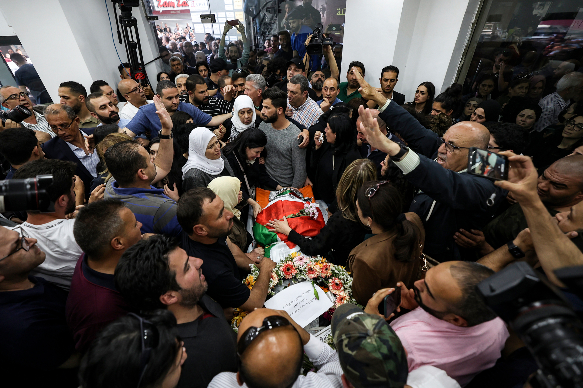 Colleagues and friends react as the Palestinian flag-draped body of veteran Al-Jazeera journalist Shireen Abu Akleh is brought to the news channel's office in the West Bank. Photo / AP