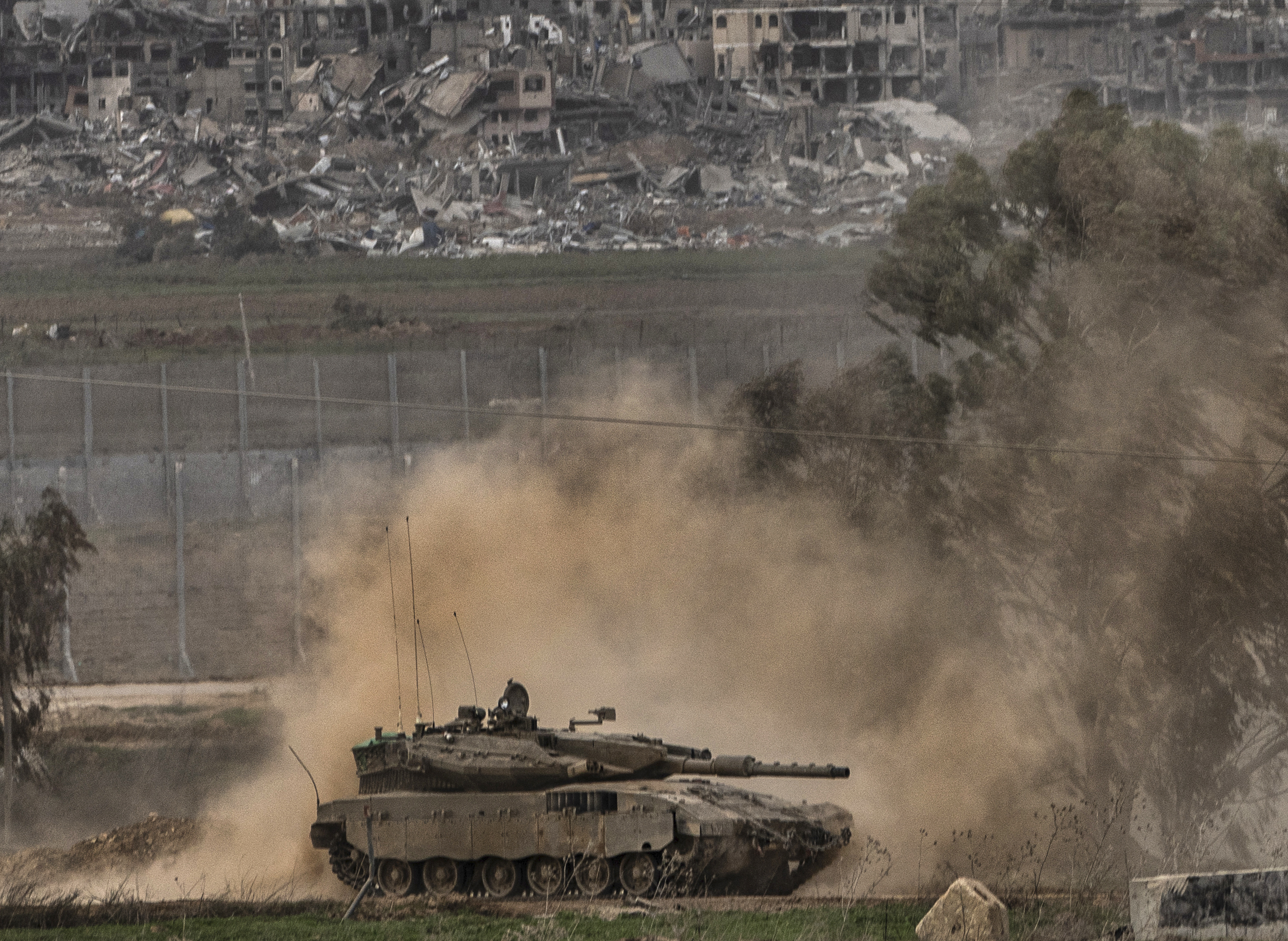 An Israeli army tank moves near the Gaza Strip border in southern Israel. The army is battling Palestinian militants across Gaza in the war ignited by Hamas' October 7 attack into Israel. Smoke from an Israeli bombardment can be seen in the background. Photo / AP