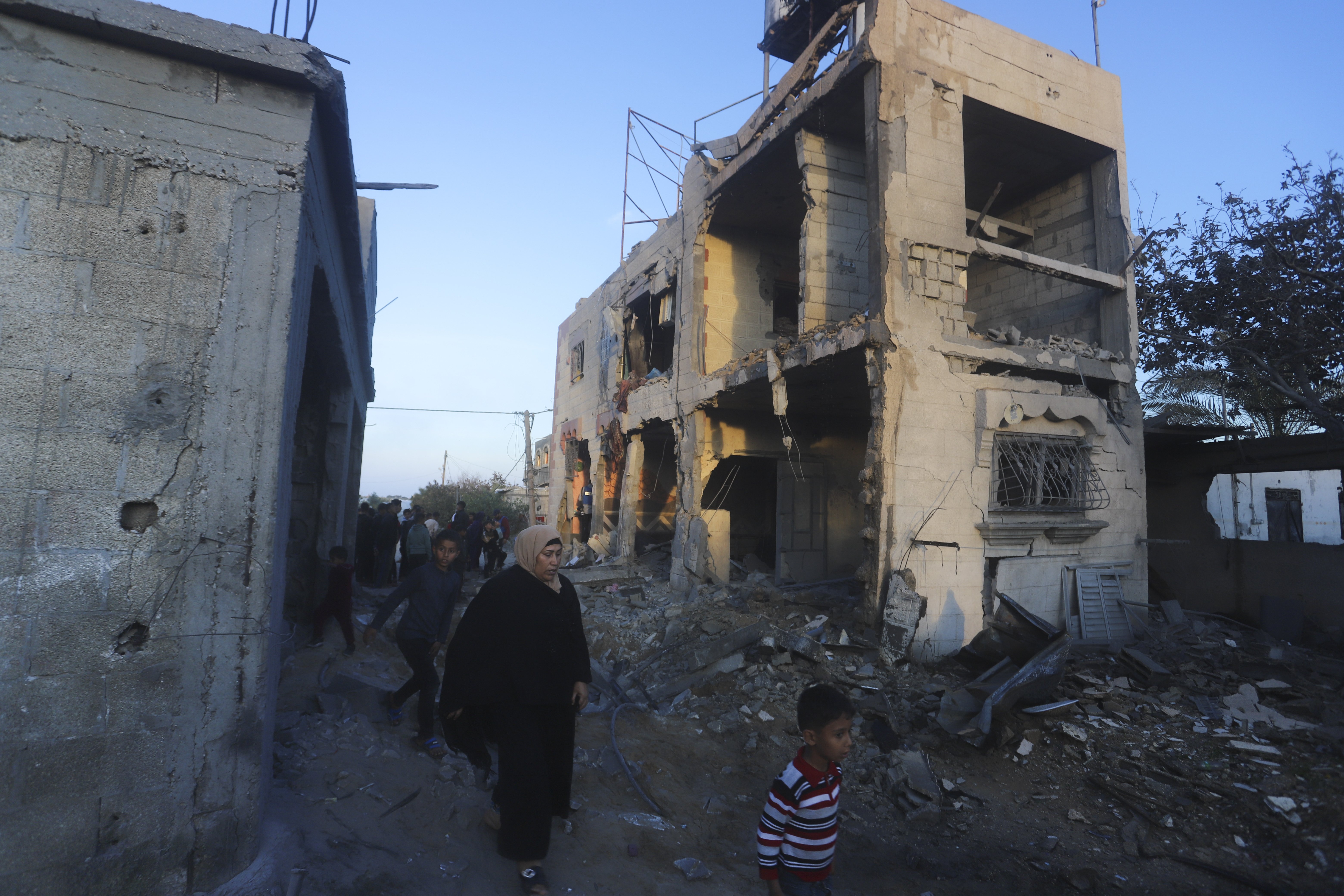 Palestinians walk by a residential building destroyed in an Israeli strike in Rafah, Gaza Strip. Photo / AP