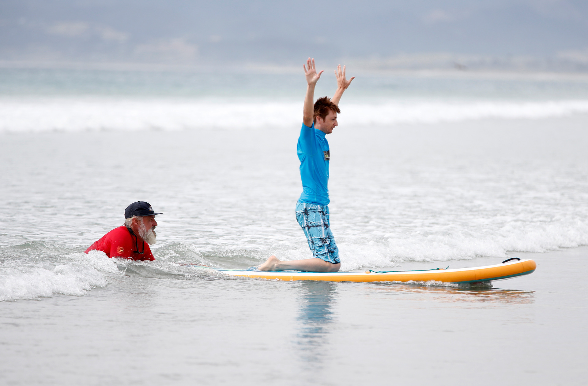 Dorian Choat from Whangārei balances on his board with help from volunteer and surf instructor Don Stevenson from Tutukaka.