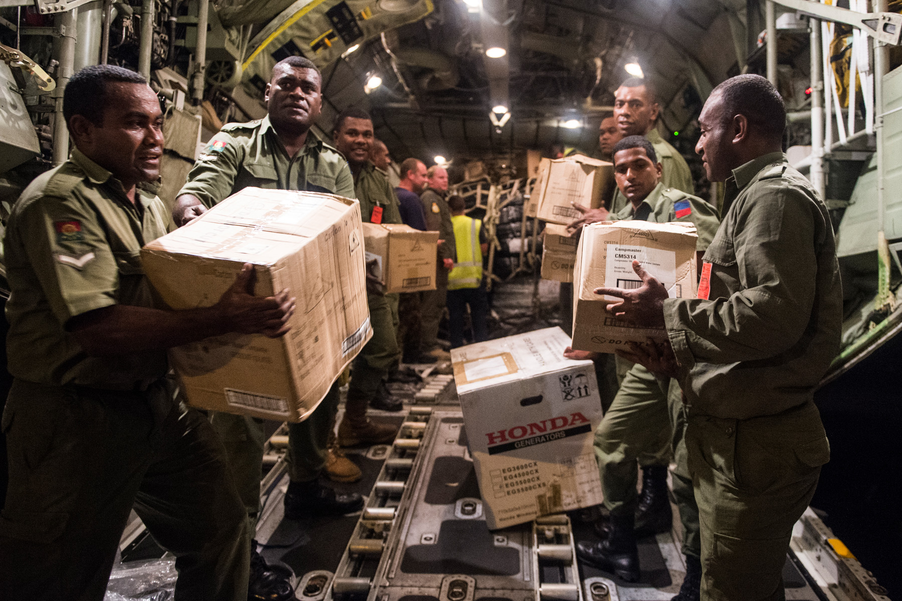 Aid supplies are unloaded by Fijian soldiers from an RNZAF C-130 Hercules in Suva, Fiji, during disaster assistance.