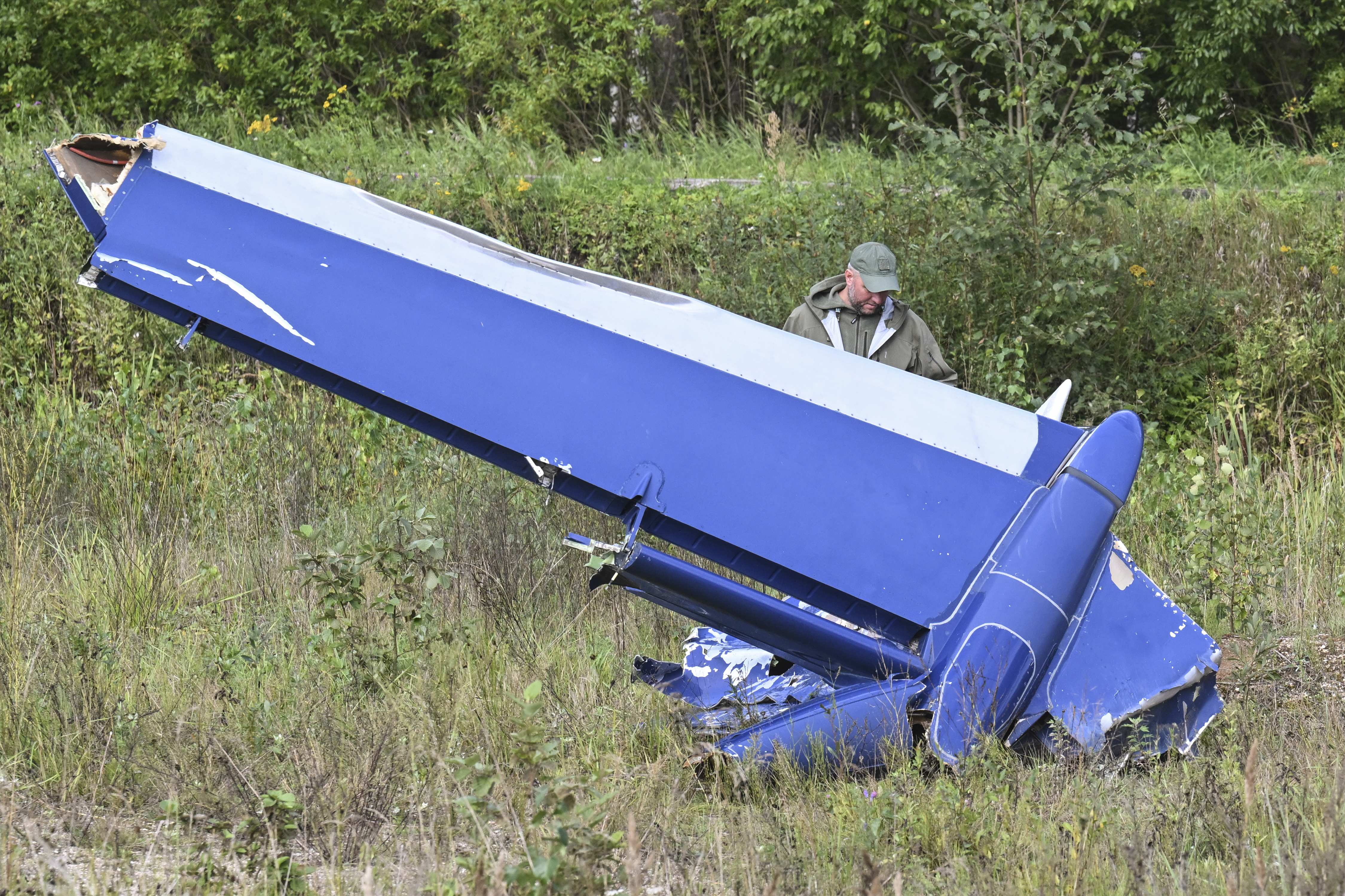 A Russian serviceman inspects a part of a crashed private jet near the village of Kuzhenkino. Photo / AP