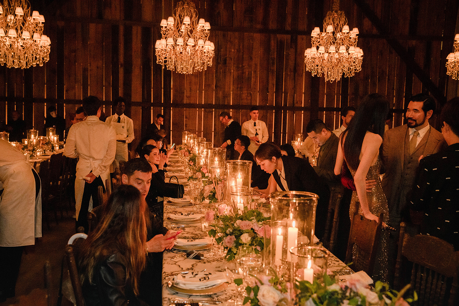 Guests sit at tables covered in floral tablecloths, gold candlestick and pink roses at the Ralph Lauren fashion show in New York. Photo / Jane Kim, The New York Times