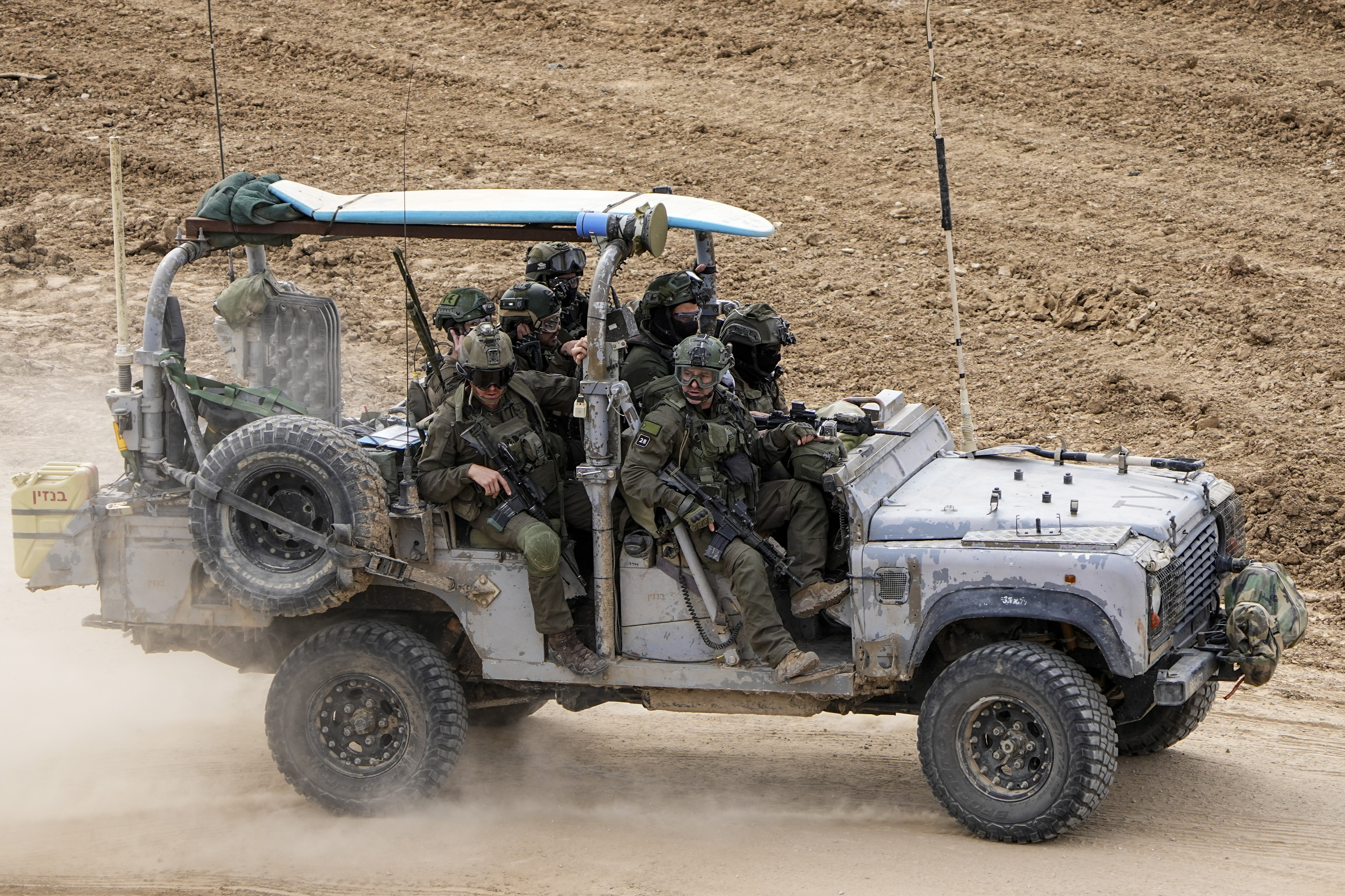 Israeli soldiers with a surfboard on the roof of their vehicle drive towards the Gaza Strip. Photo / AP