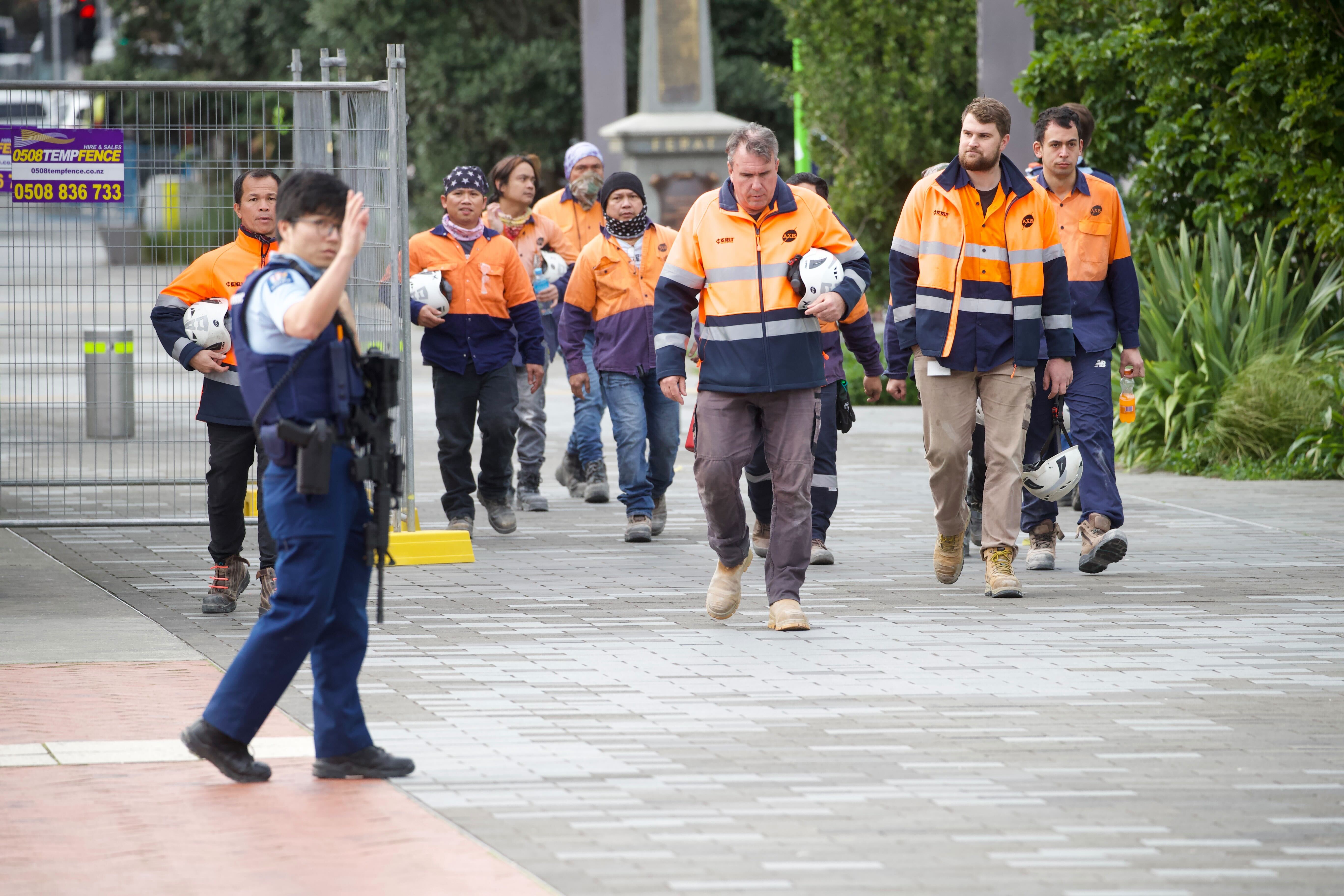 Police escorting workers from the scene on Quay St after this morning's shooting. Photo / Jason Oxenham