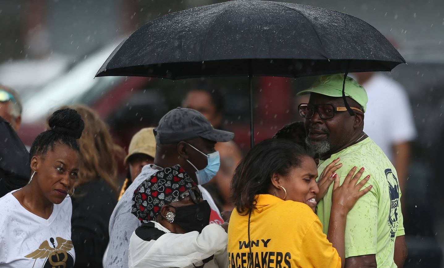 Bystanders gather under an umbrella as rain rolls in after a shooting at a supermarket in Buffalo, New York. Photo / AP