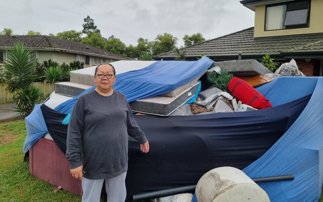 Māngere resident Pauline Ekieleu next to a skip bin full of furniture, ruined by floodwaters. Photo / Jonty Dine, RNZ