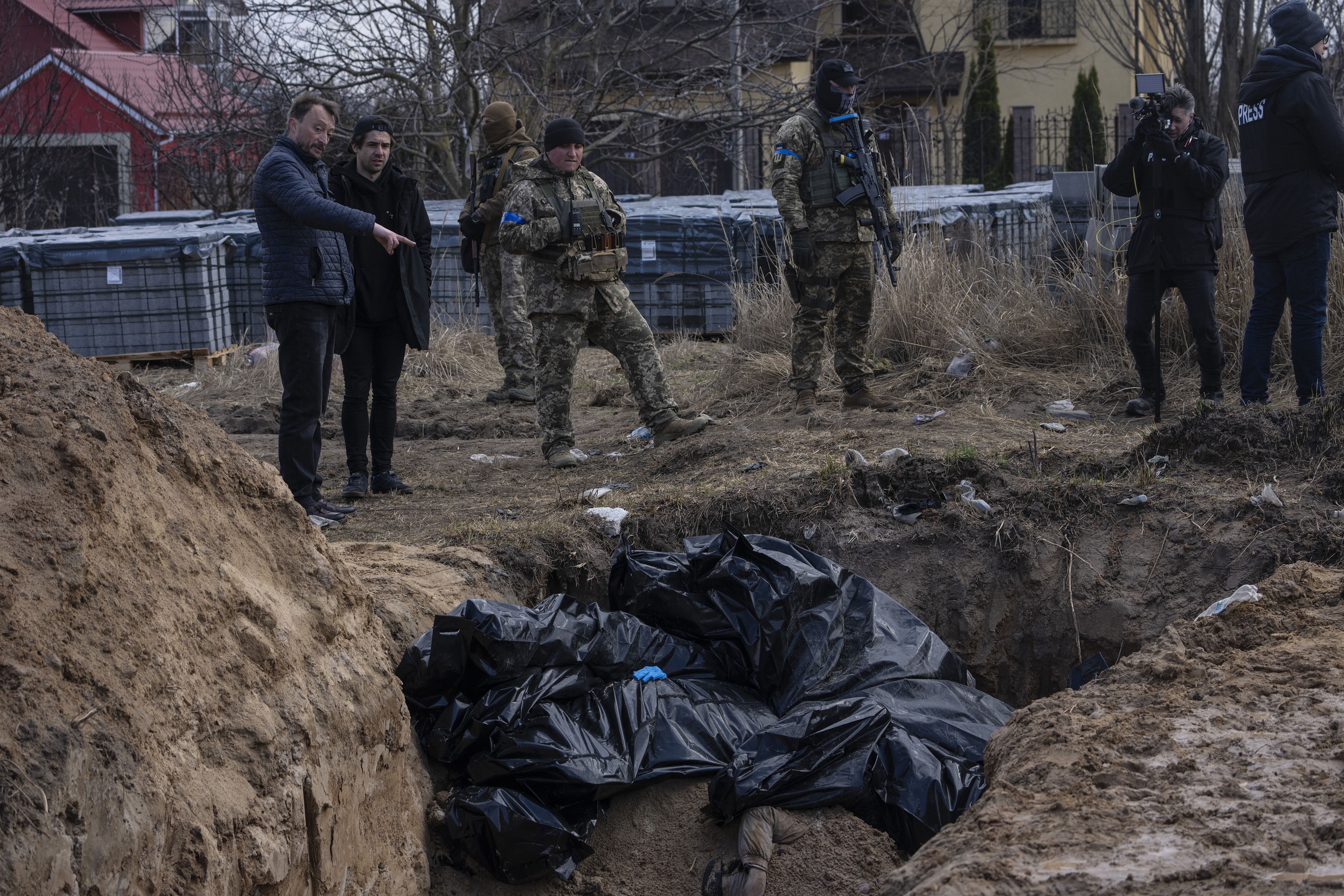 People stand next to a mass grave in Bucha, on the outskirts of Kyiv, Ukraine in April. Photo / AP