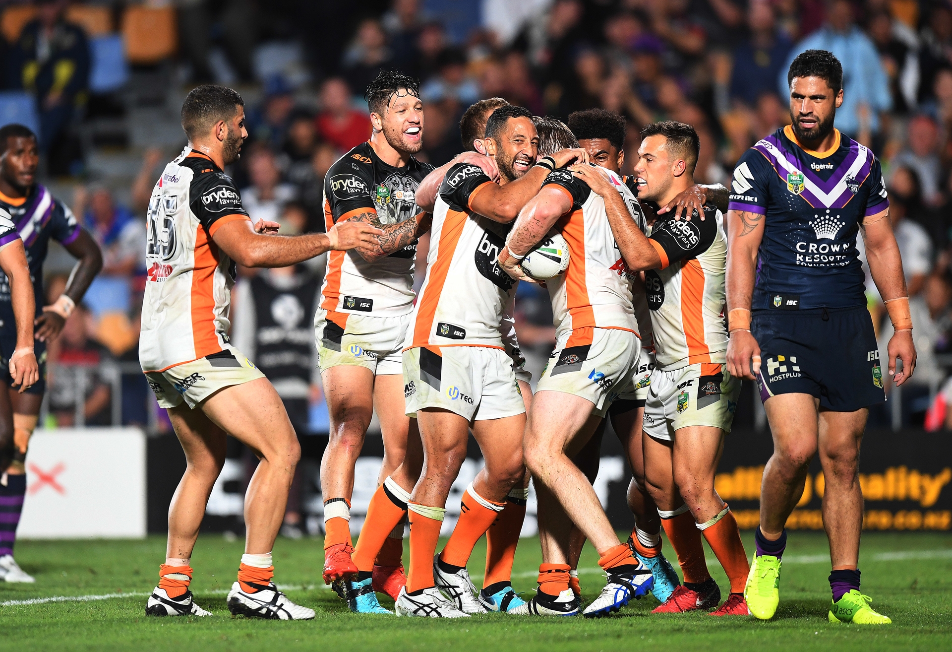 Storm forward Jesse Bromwich (right) looks unimpressed as the Tigers celebrate Josh Aloiai s four-pointer last night. Photo / Photosport.nz