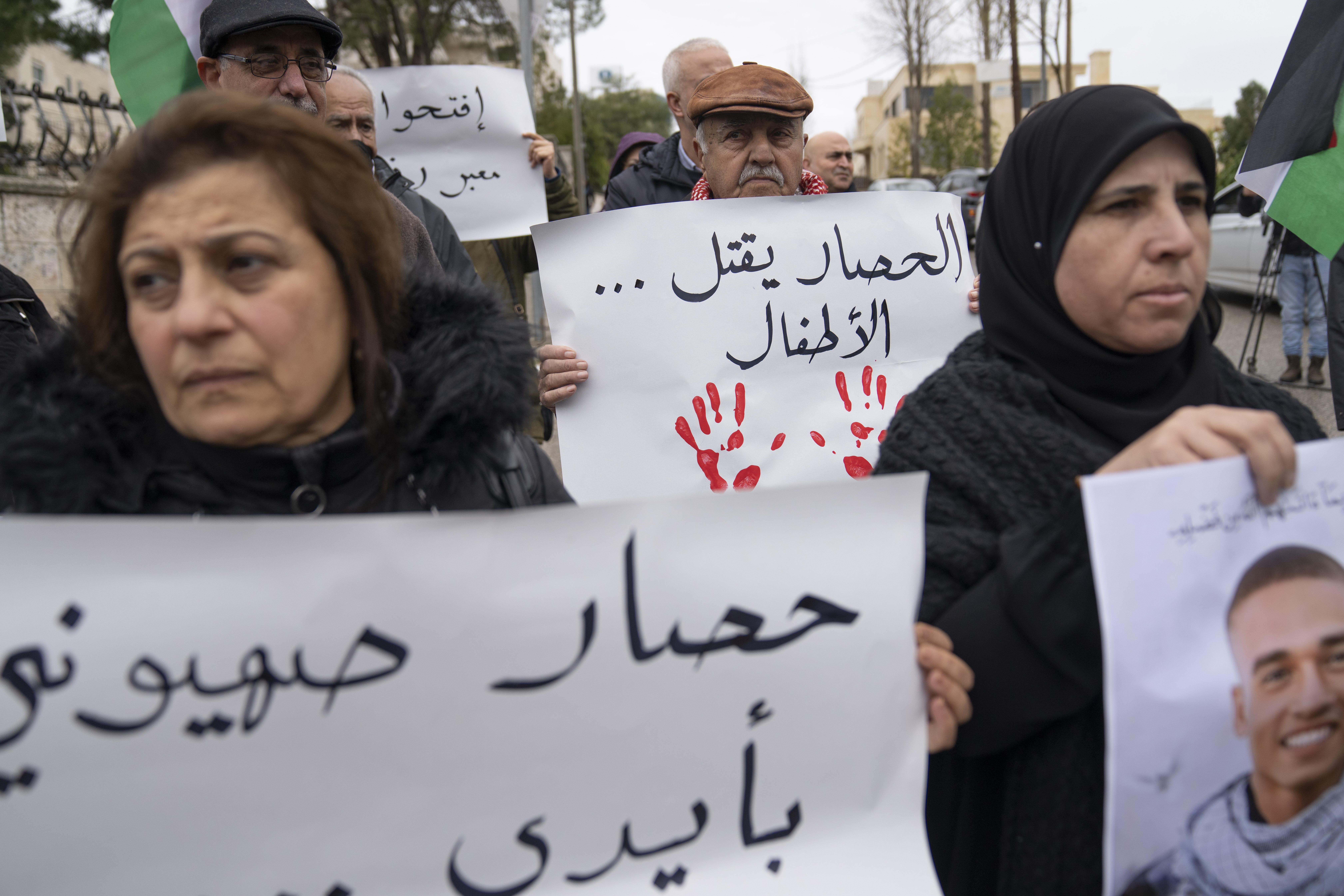 Palestinian activists carry posters - one reads 