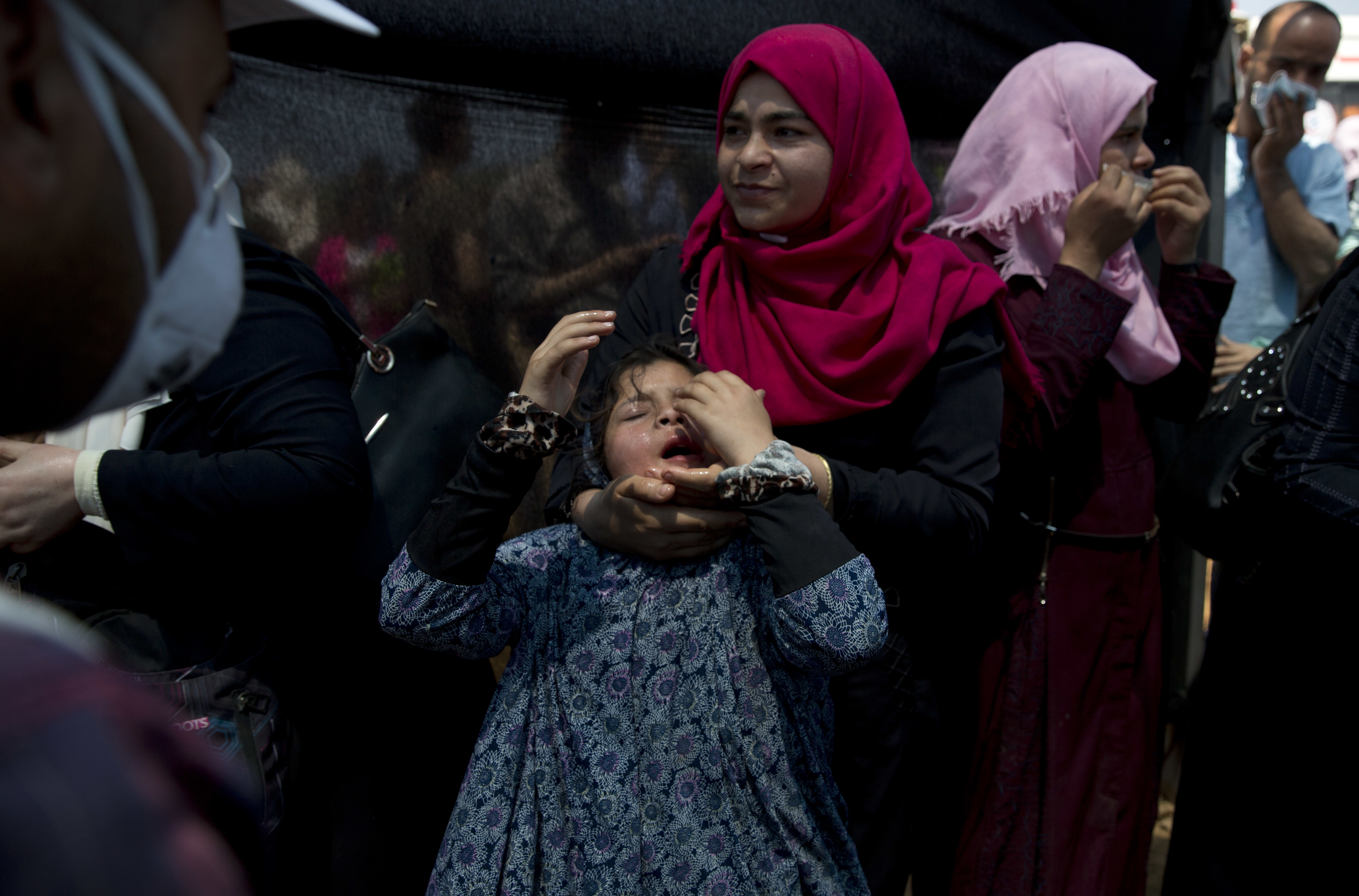 A Palestinian woman holds her daughter suffering from teargas inhalation during a protest at the Gaza Strip. Photo / AP 
