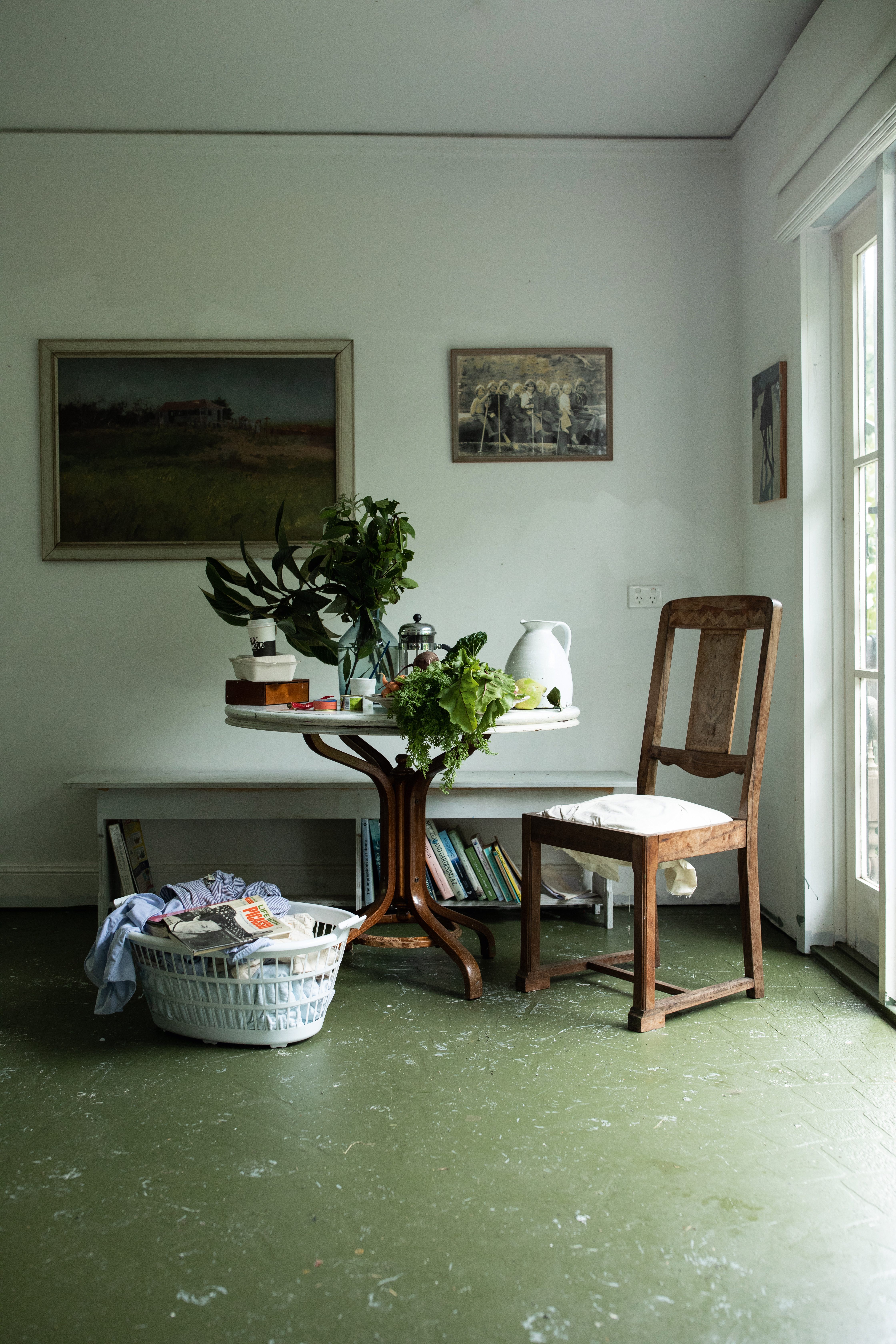 Corner of Zoe’s kitchen with leafy vegetables harvested from her garden. On the wall is a painting by Thomas McAuley called 'Cane Barracks Innisfail'; and to the right an old photograph of Zoe’s siblings and friends in the Snowy Mountains. Photo / Supplied