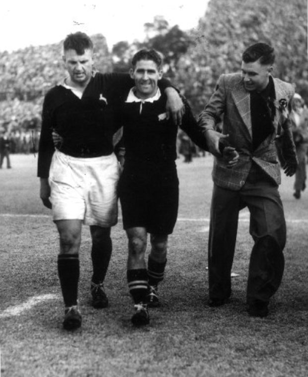 All Black Fred Allen smiles for the camera walking off the field with Springbok F. Du Plessis after the Springboks won the second rugby test 12 -6. Photo / Rand Daily Mail