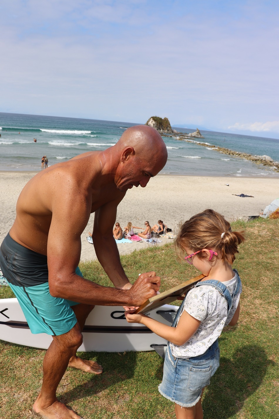 Kelly Slater taking the time to sign a framed surfing fin for young Vivienne Buckle. Photo / Ella Buckle