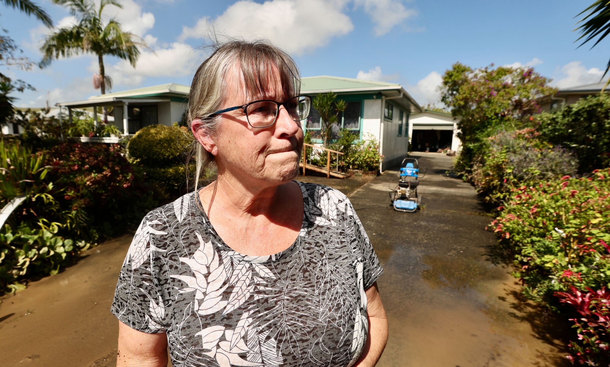 Sandra Shackleton helping to clean up her father's house after he was evacuated last night in Donalds Lane after flooding in Kaitāia. Photo / Jason Dorday