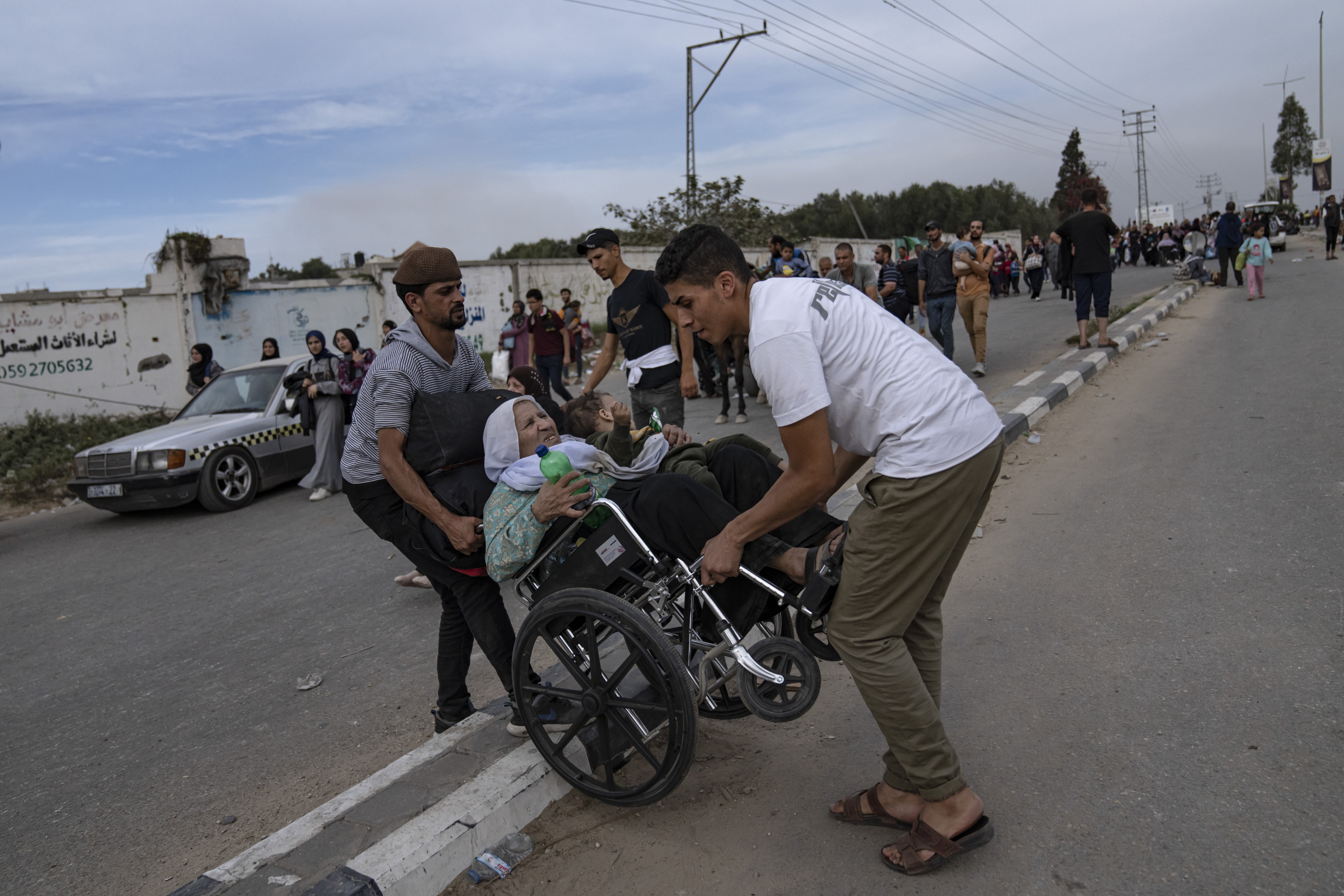 Two men help a woman in a wheelchair to evacuate on Salah al-Din Street in Bureij on November 11. Photo / AP  