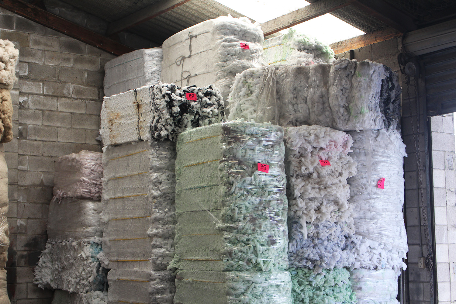 Processed pallets of textile waste sit in the warehouse at Textile Products, which Ben Willis says are coloured by the unique mix of fabrics run through the machine. Photo / Madeleine Crutchley