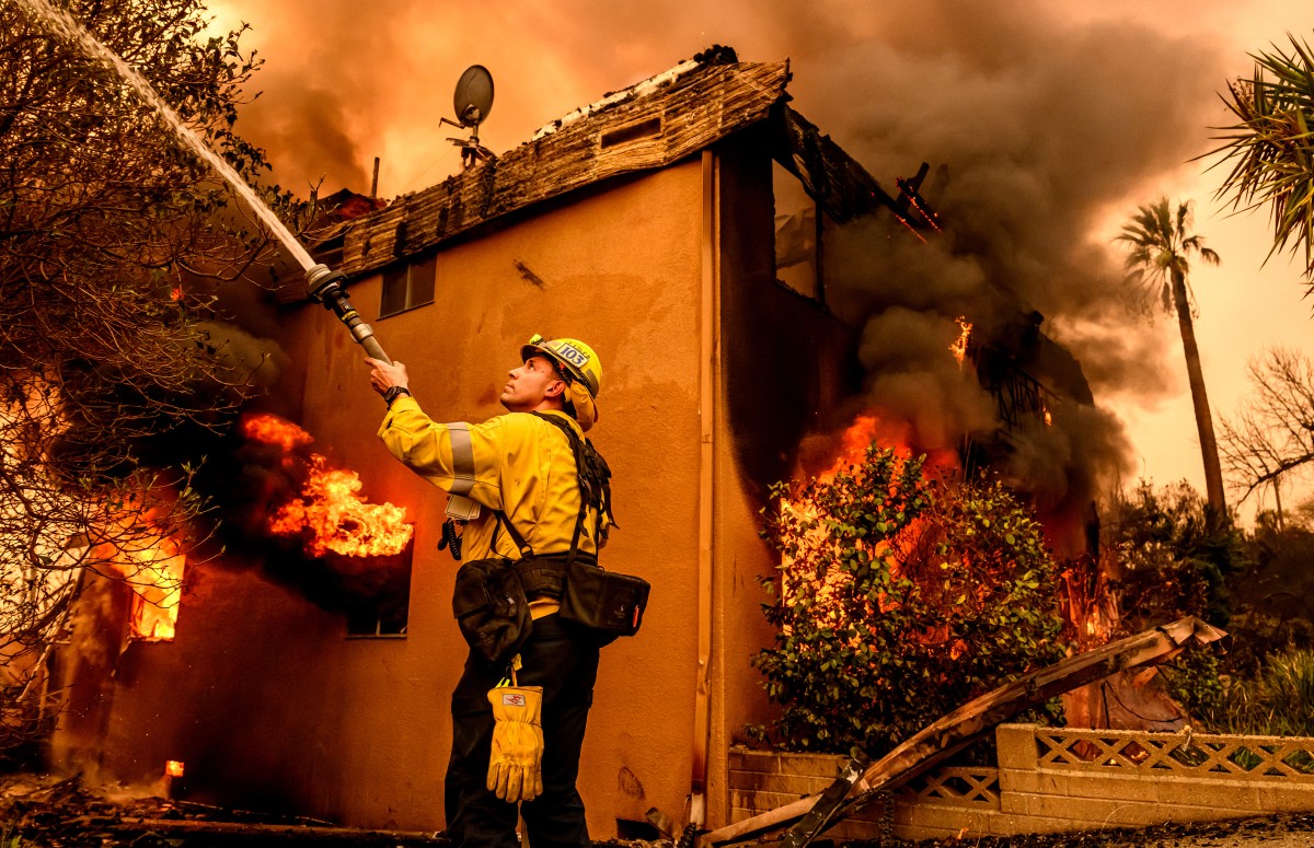 A firefighter douses flames as an apartment building burns during the Eaton fire in the Altadena area of Los Angeles county, California. Photo / AFP