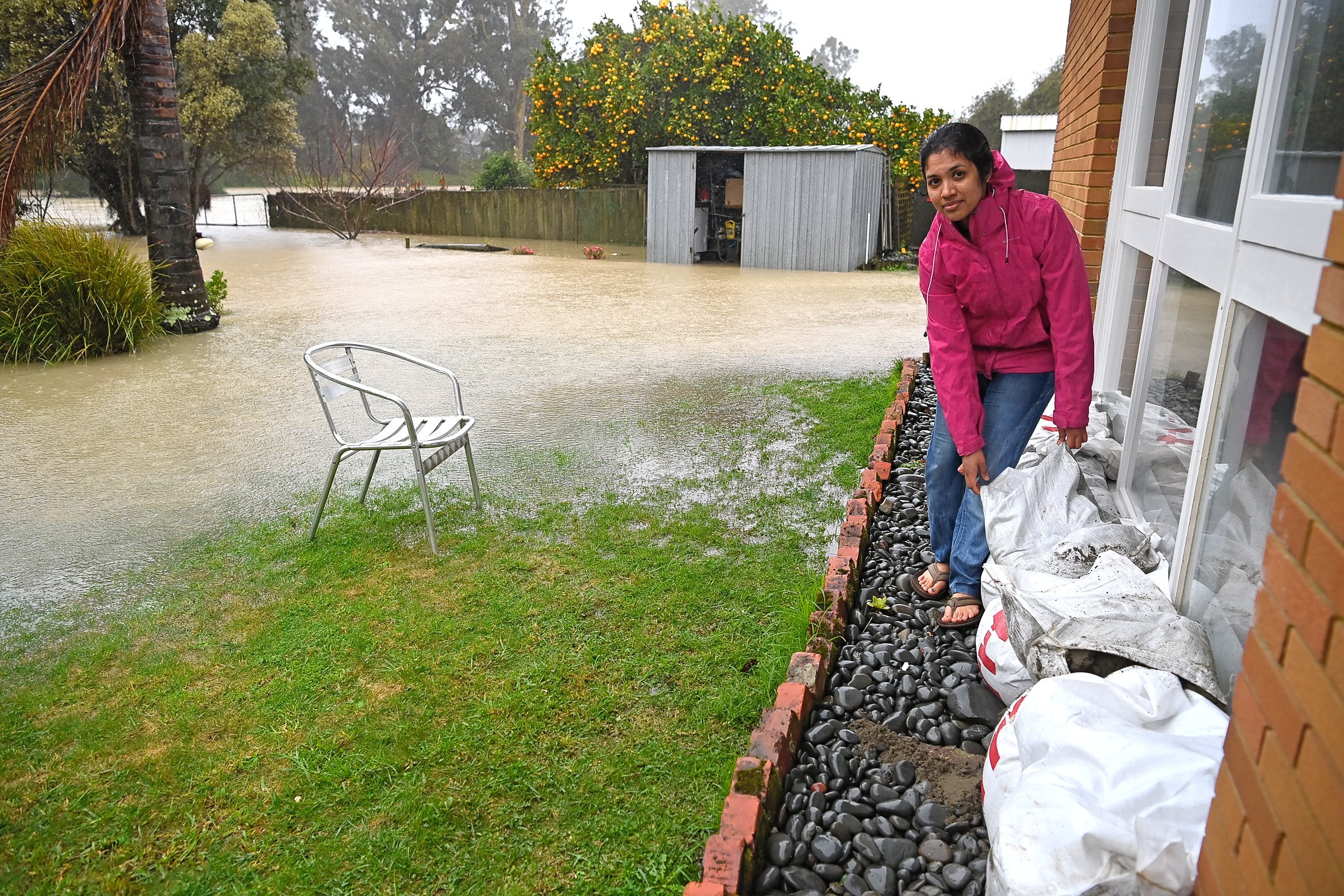 Asha John lines sandbags against her Fergusson Drive home in Gisborne yesterday as the Taruheru River floods the backyard. Some basements and garages were flooded but there were no reports of major house flooding,
Photo / Paul Rickard