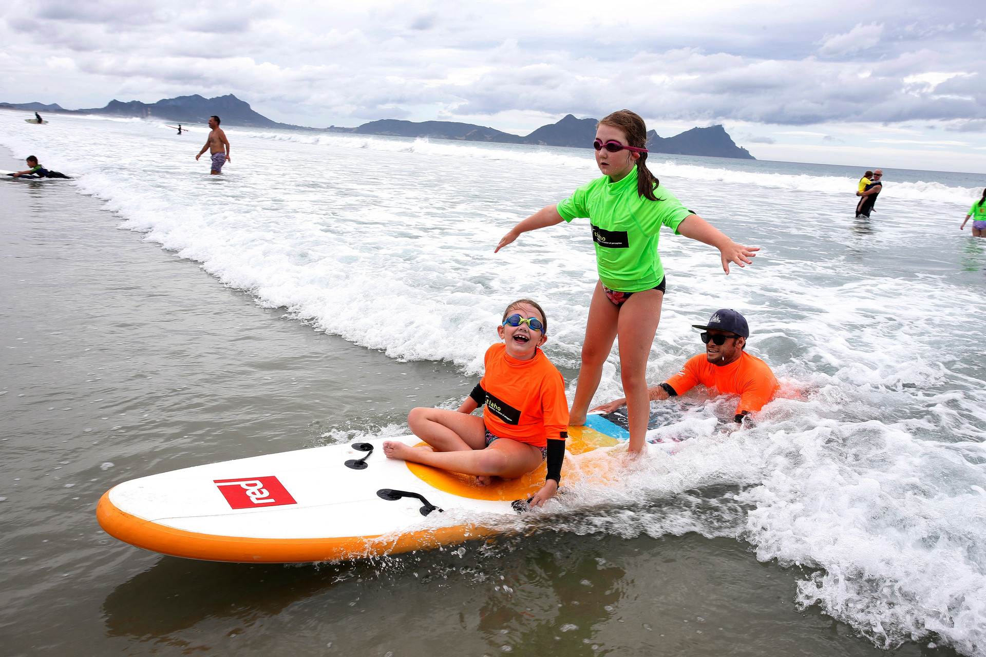 Raven, 8, and Charlize Casey, 10, with volunteer surf instructor Simon Egginton from Tutukaka.