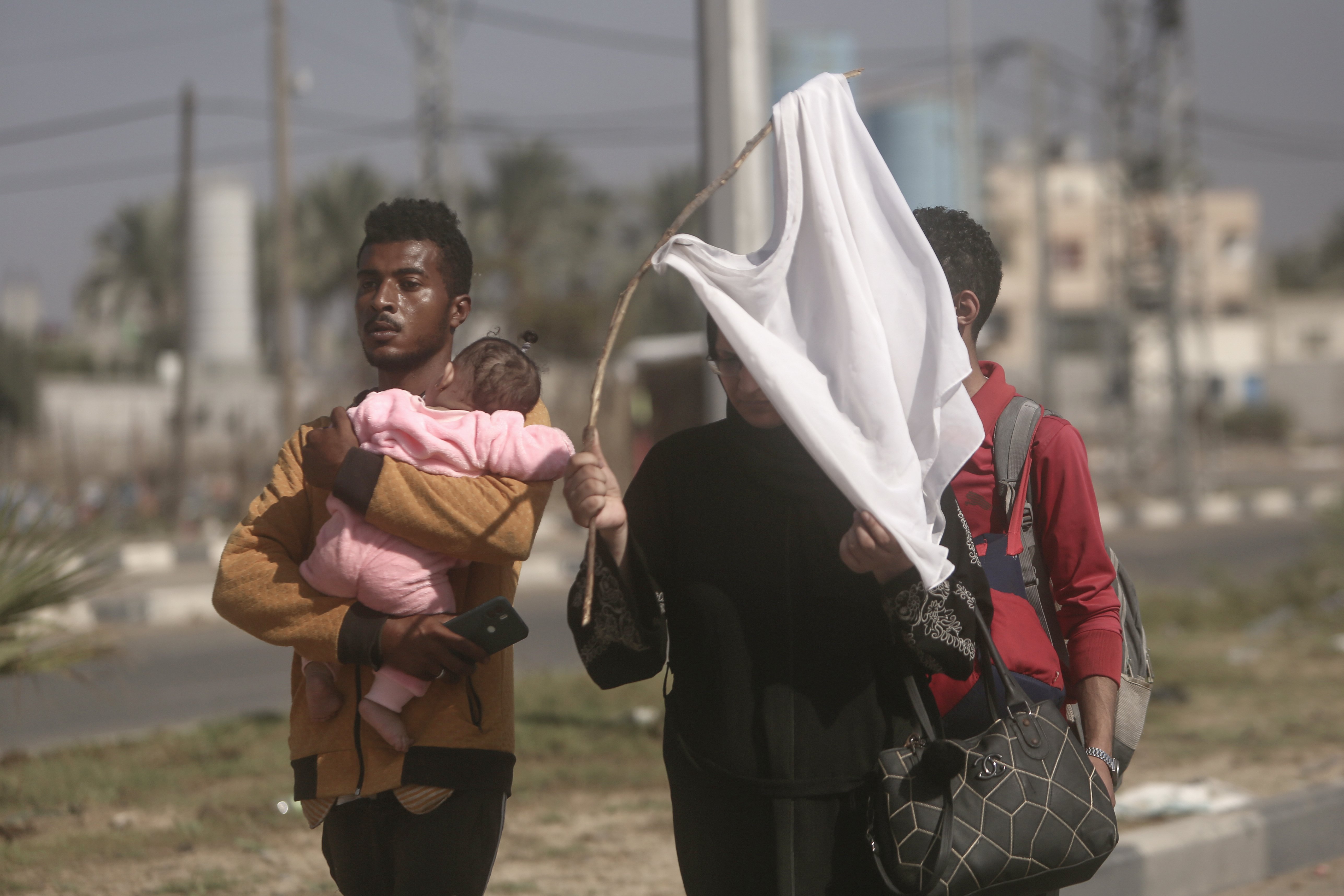 A woman holds up a stick with a shirt attached as a white flag to prevent being shot, as Palestinians flee Gaza City to the southern Gaza Strip on Salah al-Din street in Bureij in November. Photo / AP