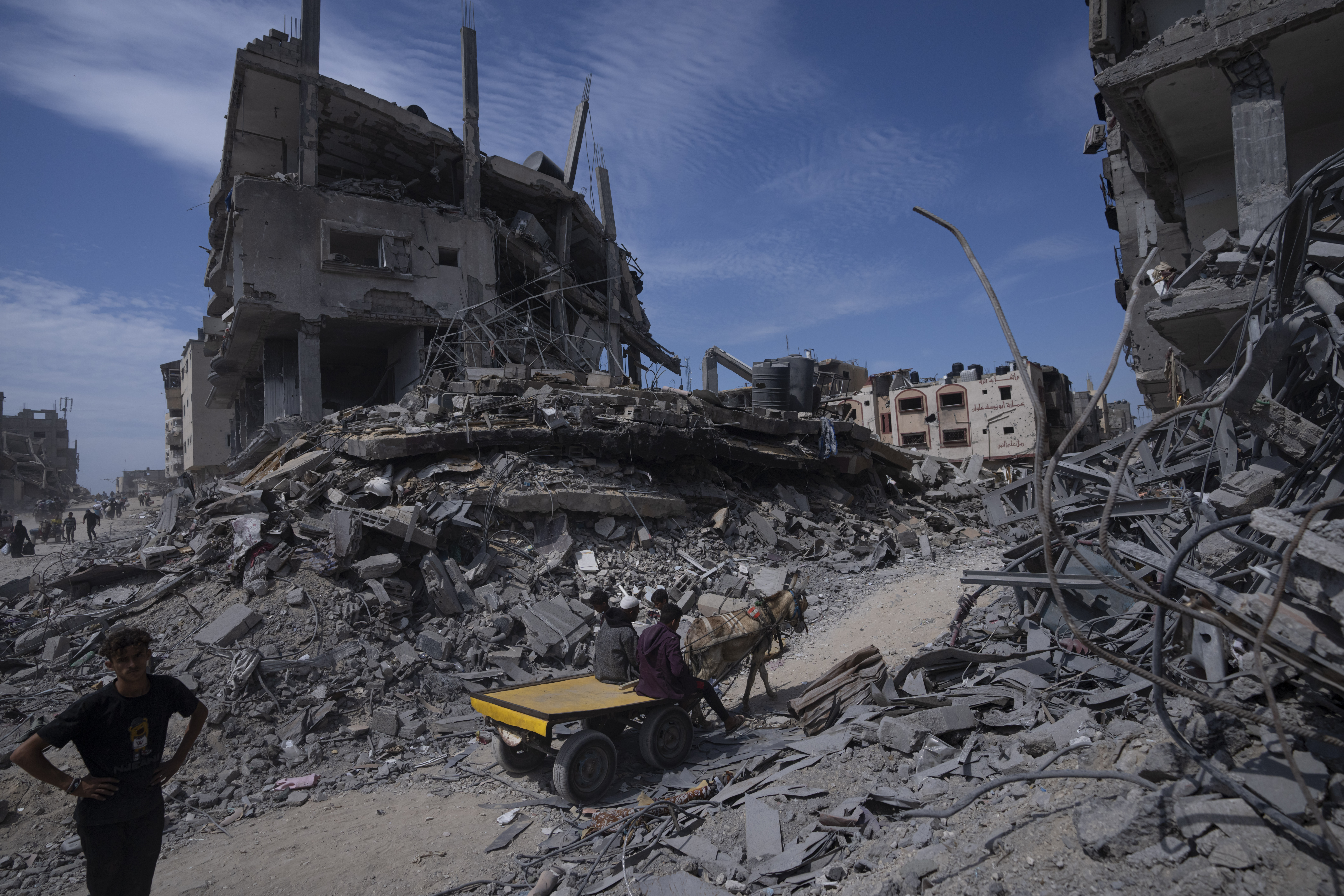 Palestinians walk through the destruction in the wake of an Israeli air and ground offensive in Khan Younis, southern Gaza Strip. Photo / AP