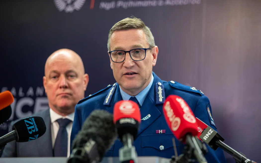 Former Deputy Commissioner Jevon McSkimming addresses media at a press conference, while Prime Minister Christopher Luxon watches on. Photo / RNZ, Reece Baker